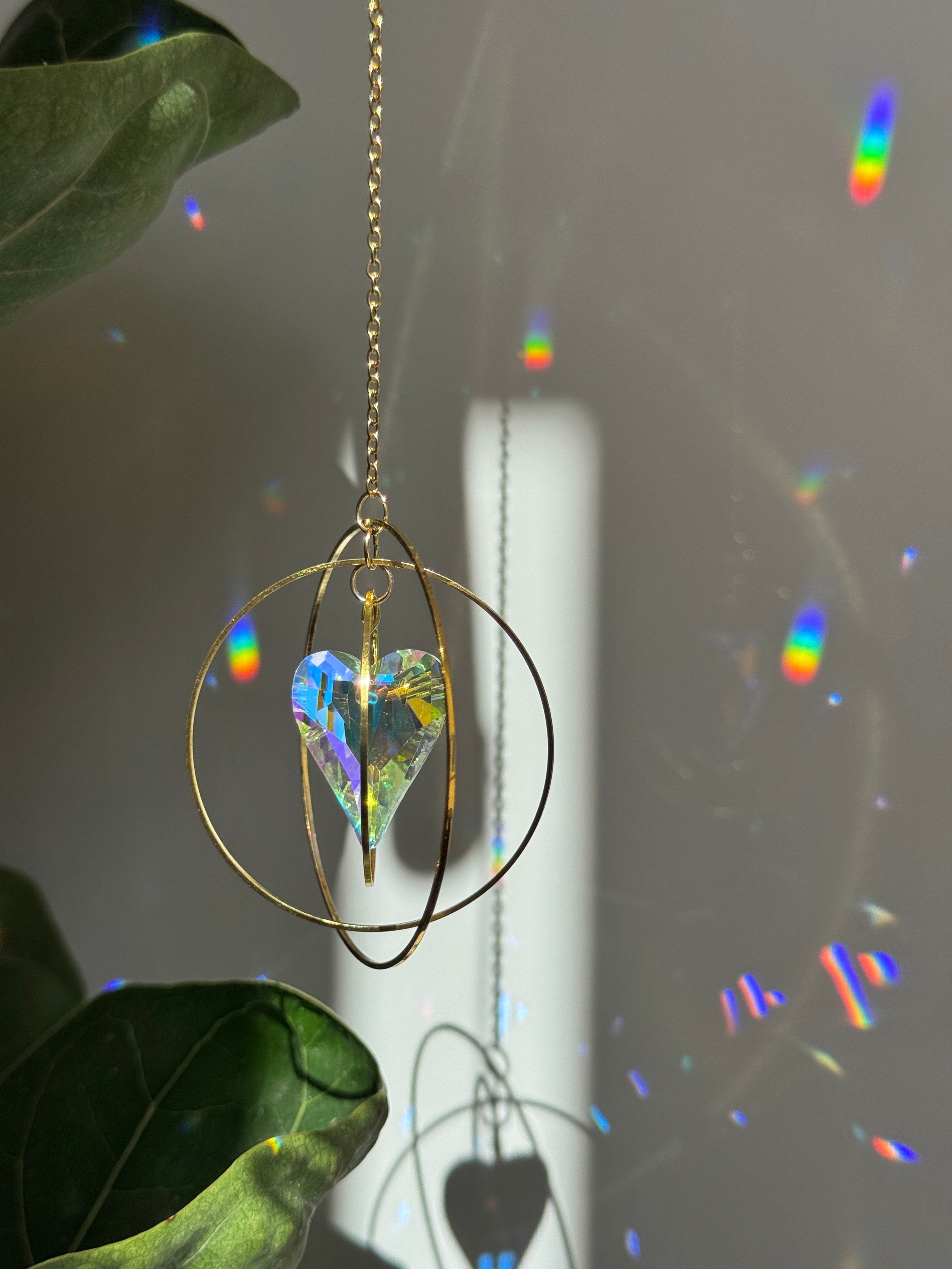 A hanging orbital suncatcher with shimmering heart shaped glass crystal 