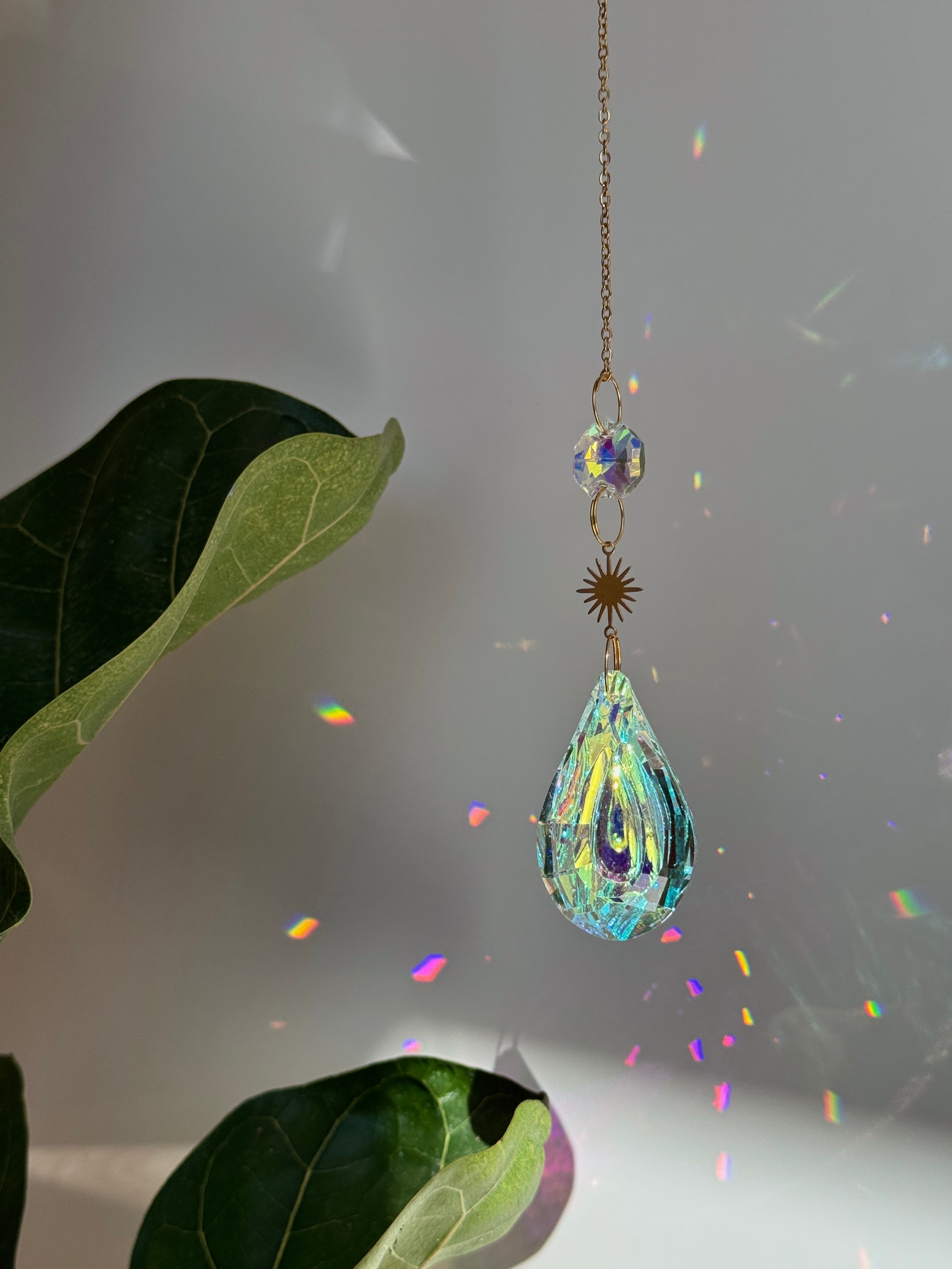 Hanging geometric suncatcher with crystal droplets and metal discs surrounded by plants