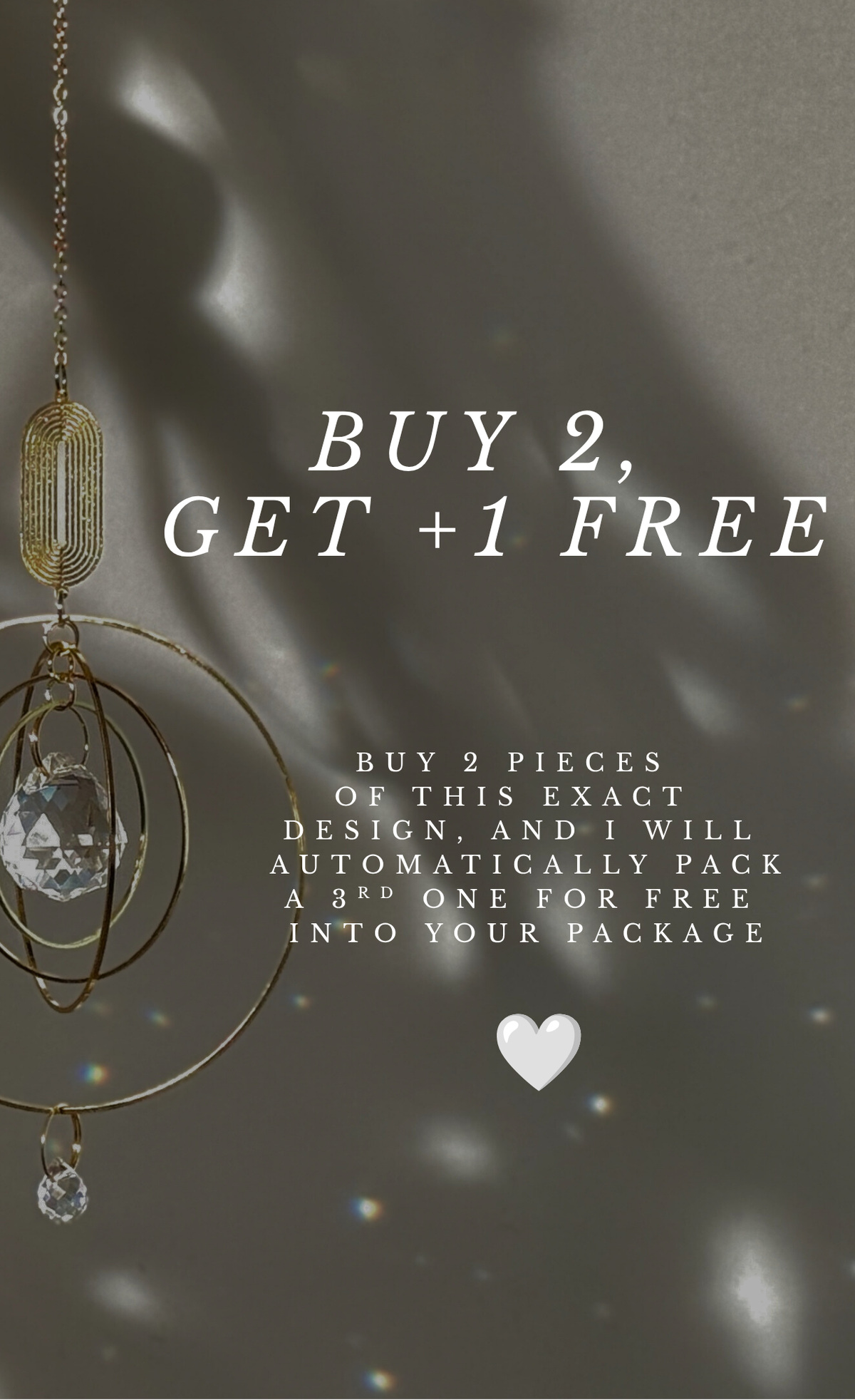 Promotional graphic with text reading 'BUY 2, GET +1 FREE' over a dark gray background with soft light streaks. A hanging gold-toned decorative object with a clear faceted crystal is shown on the left, and smaller text below explains a free packaging bonus.