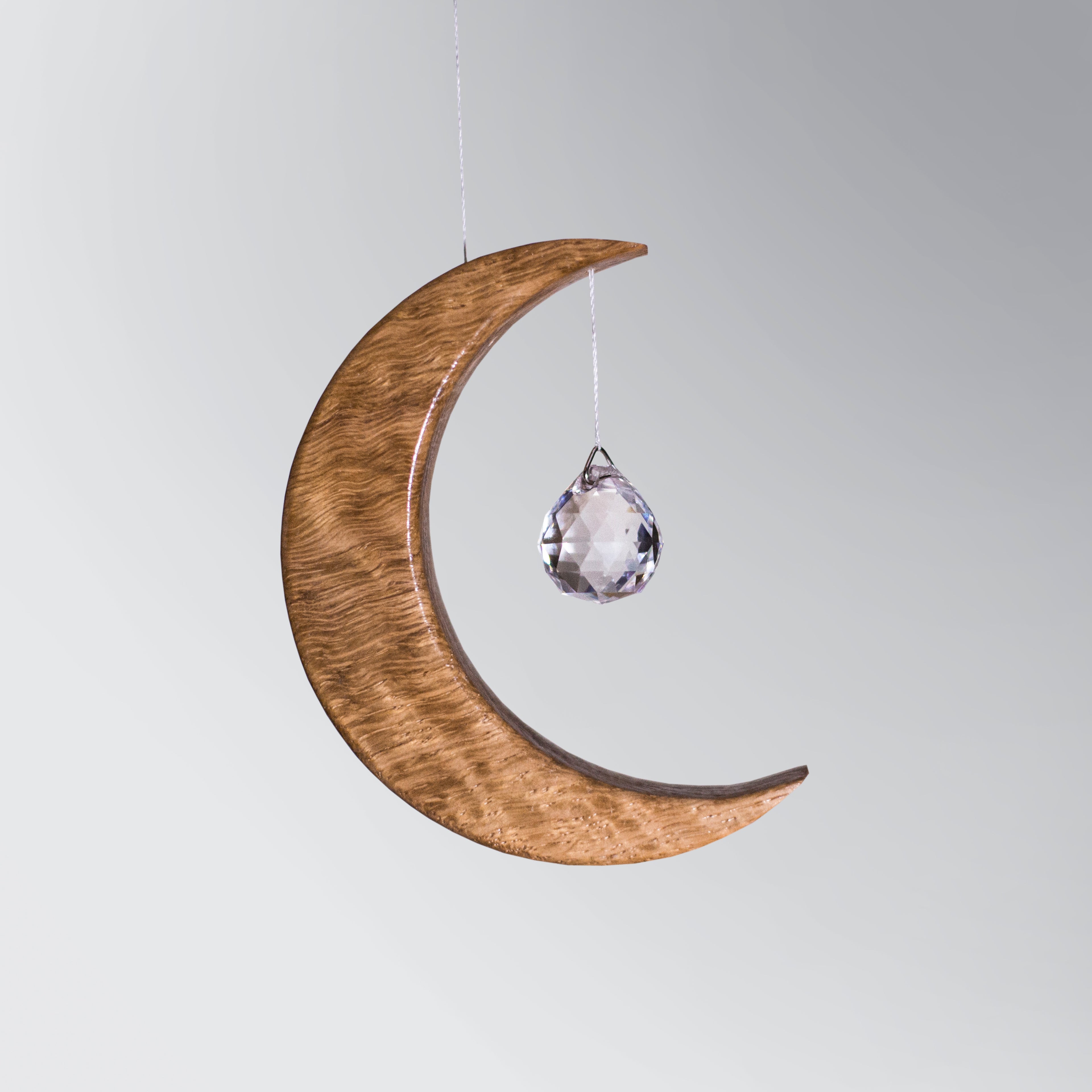 Signature Crescent Mond Sonnenfänger: Handcrafted Oak Wood Moon with 4cm Asfour Kristallprisma hanging in sunlight.