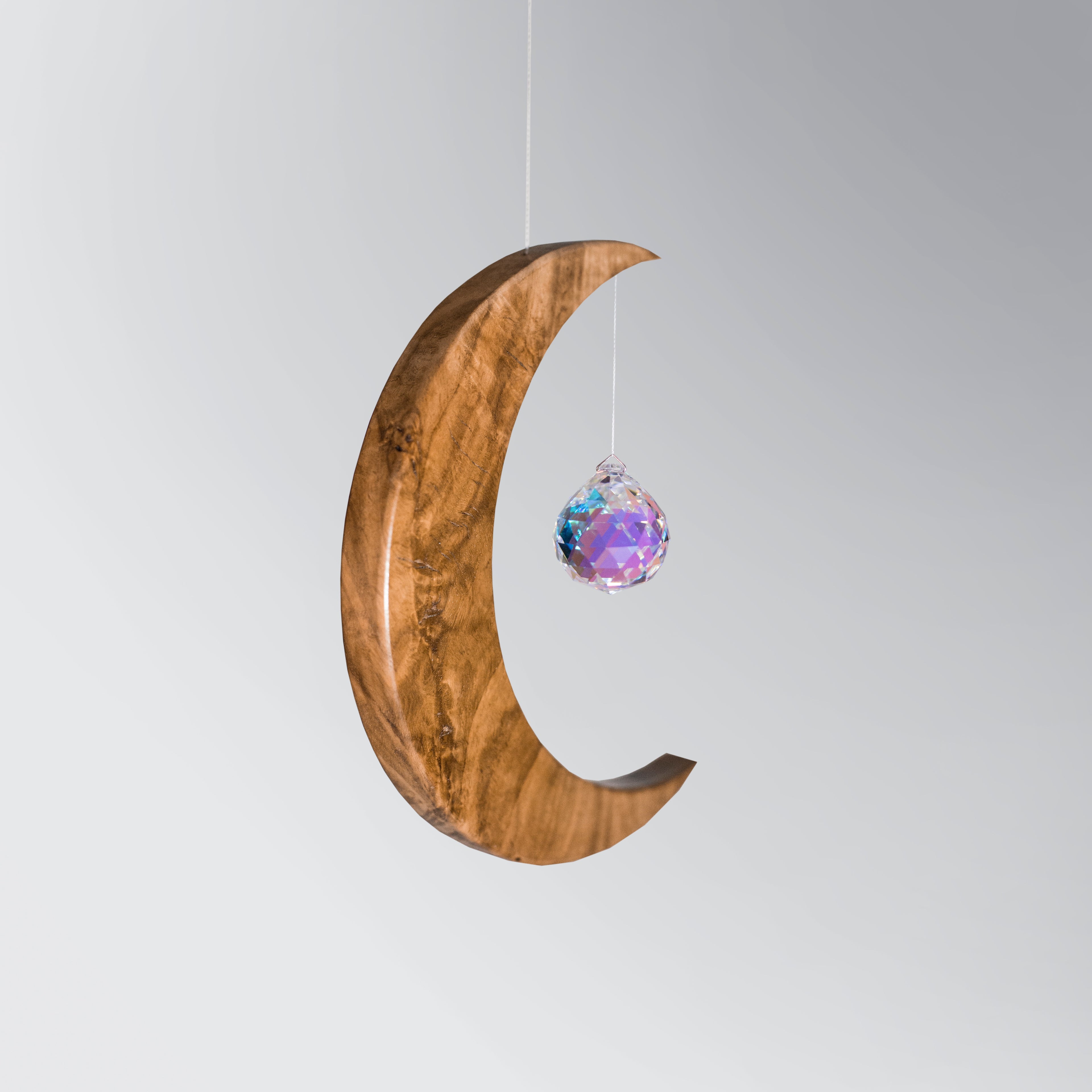 Signature Crescent Mond Sonnenfänger: Handcrafted Oak Wood Moon with 4cm Asfour Kristallprisma hanging in sunlight.