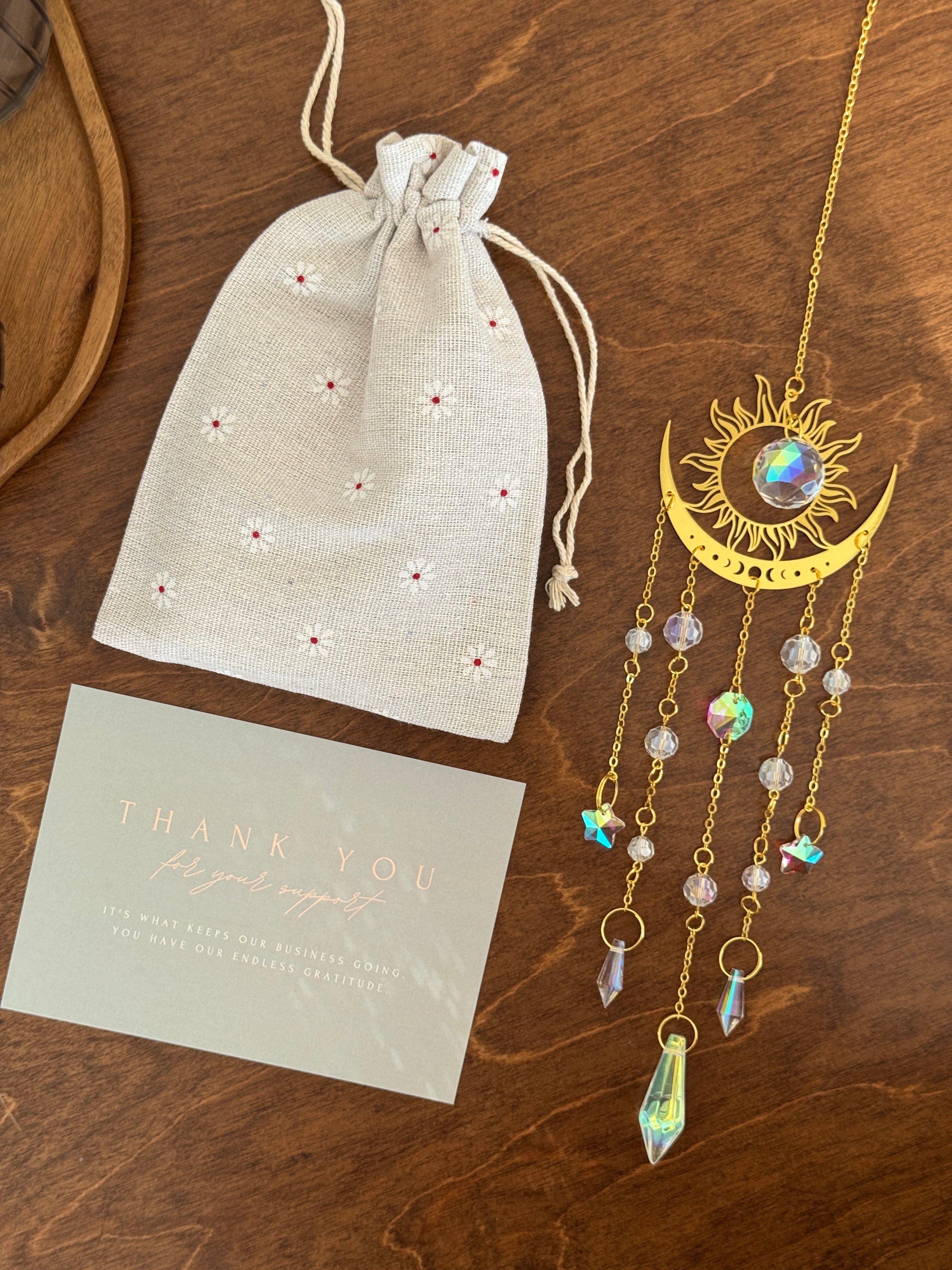 The Aura suncatcher featuring a gold crescent moon and sunburst with hanging crystal stars and prisms. Handgefertigter Sonnenfänger casting vivid rainbows on the wall. Boho-Stil Fensterdeko and magical Lichtreflexe home ornament.