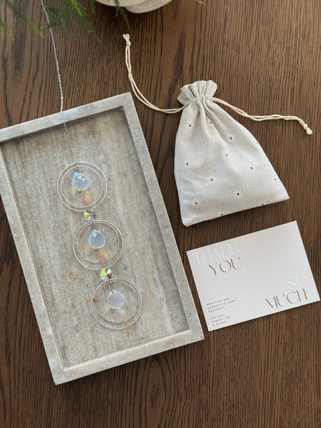 A silver-toned triple-tiered suncatcher made of stainless steel hoops. Each of the three orbits holds a clear crystal sphere with an AB coating, reflecting iridescent rainbow colors against a neutral background.