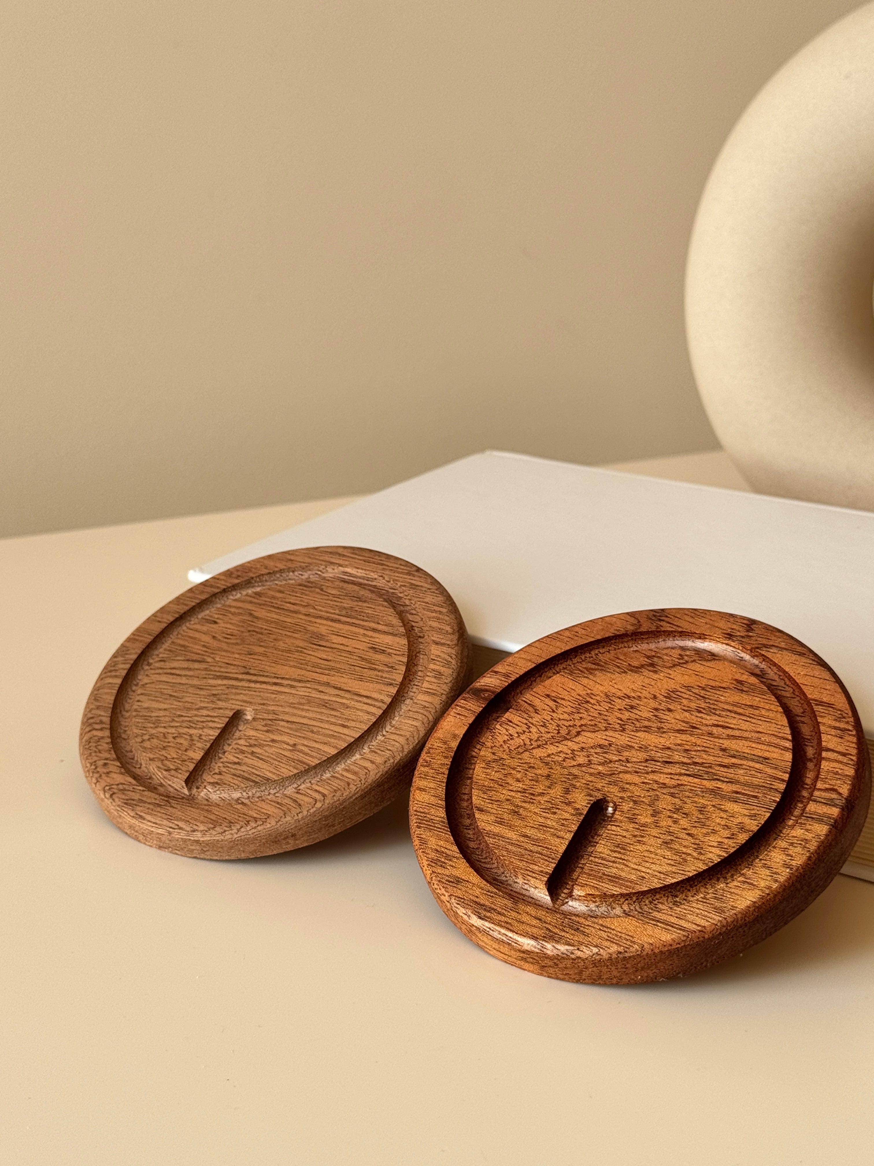 Wooden coasters with circular designs on a beige surface