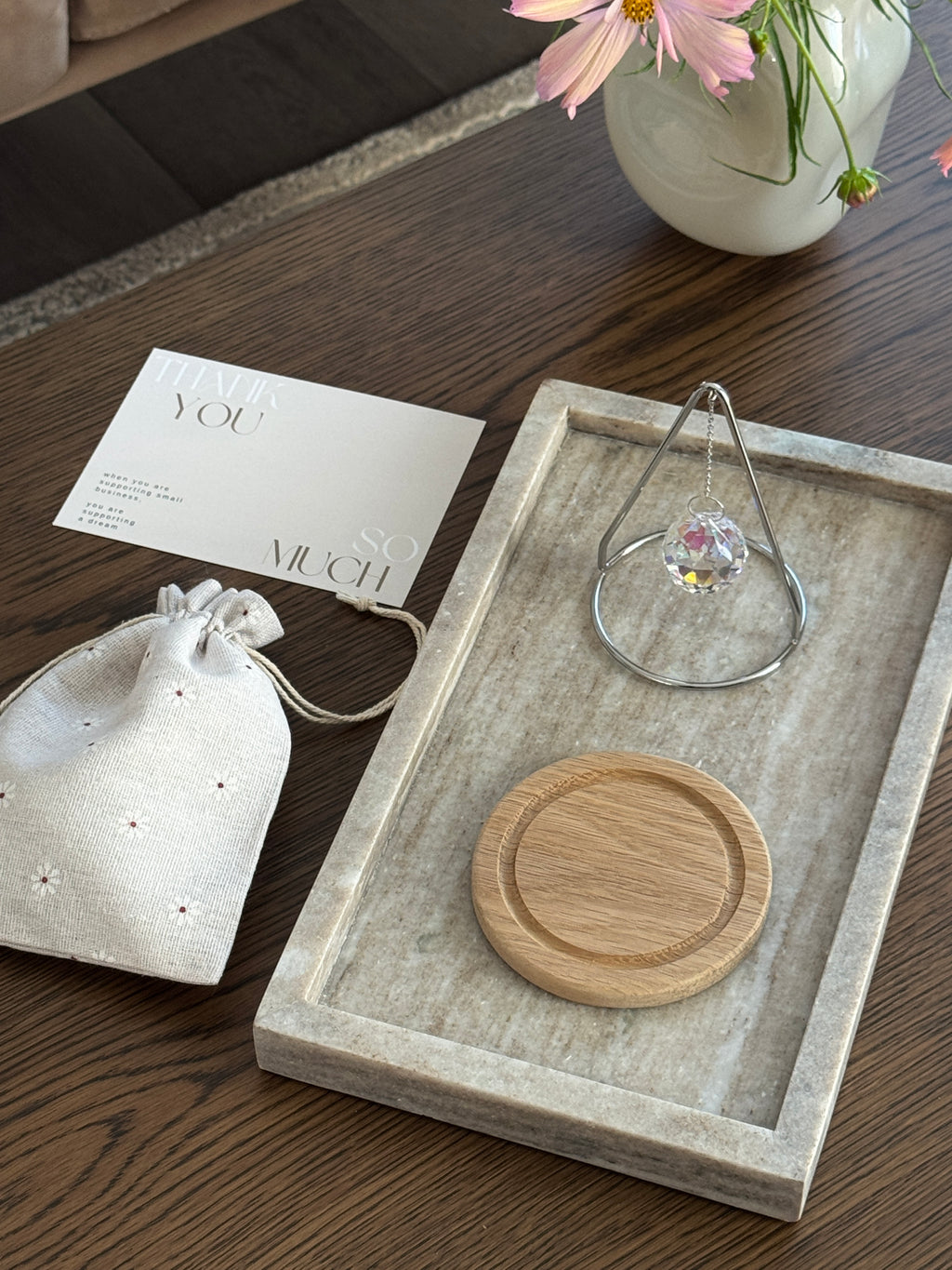 The Triangle Sonnenfänger: A modern crystal prism suncatcher with a handcrafted oak wood base and stainless steel frame, creating magical rainbow reflections.