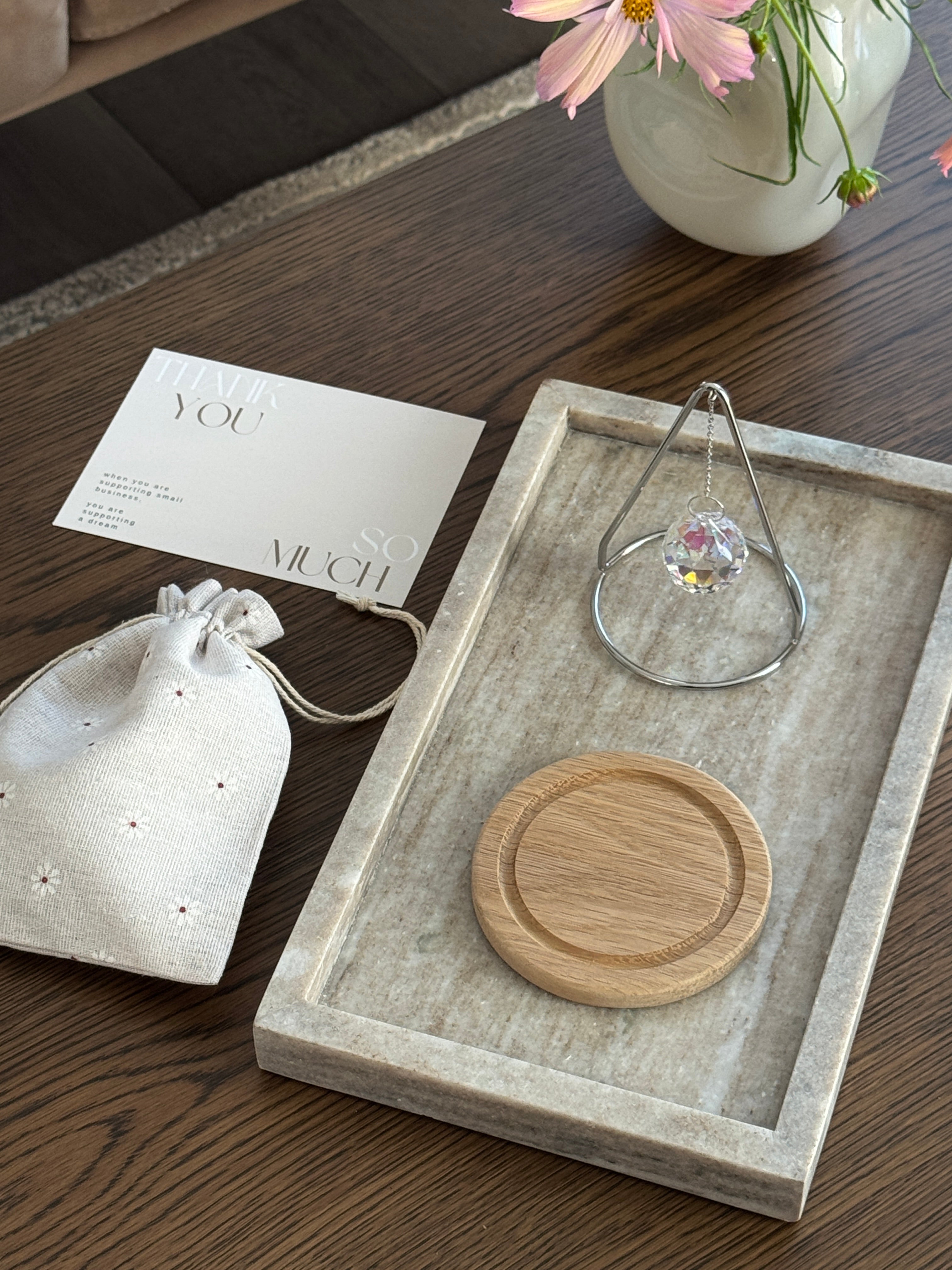 The Triangle Sonnenfänger: A modern crystal prism suncatcher with a handcrafted oak wood base and stainless steel frame, creating magical rainbow reflections.
