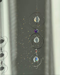 A silver-toned triple-tiered suncatcher made of stainless steel hoops. Each of the three orbits holds a clear crystal sphere with an AB coating, reflecting iridescent rainbow colors against a neutral background.