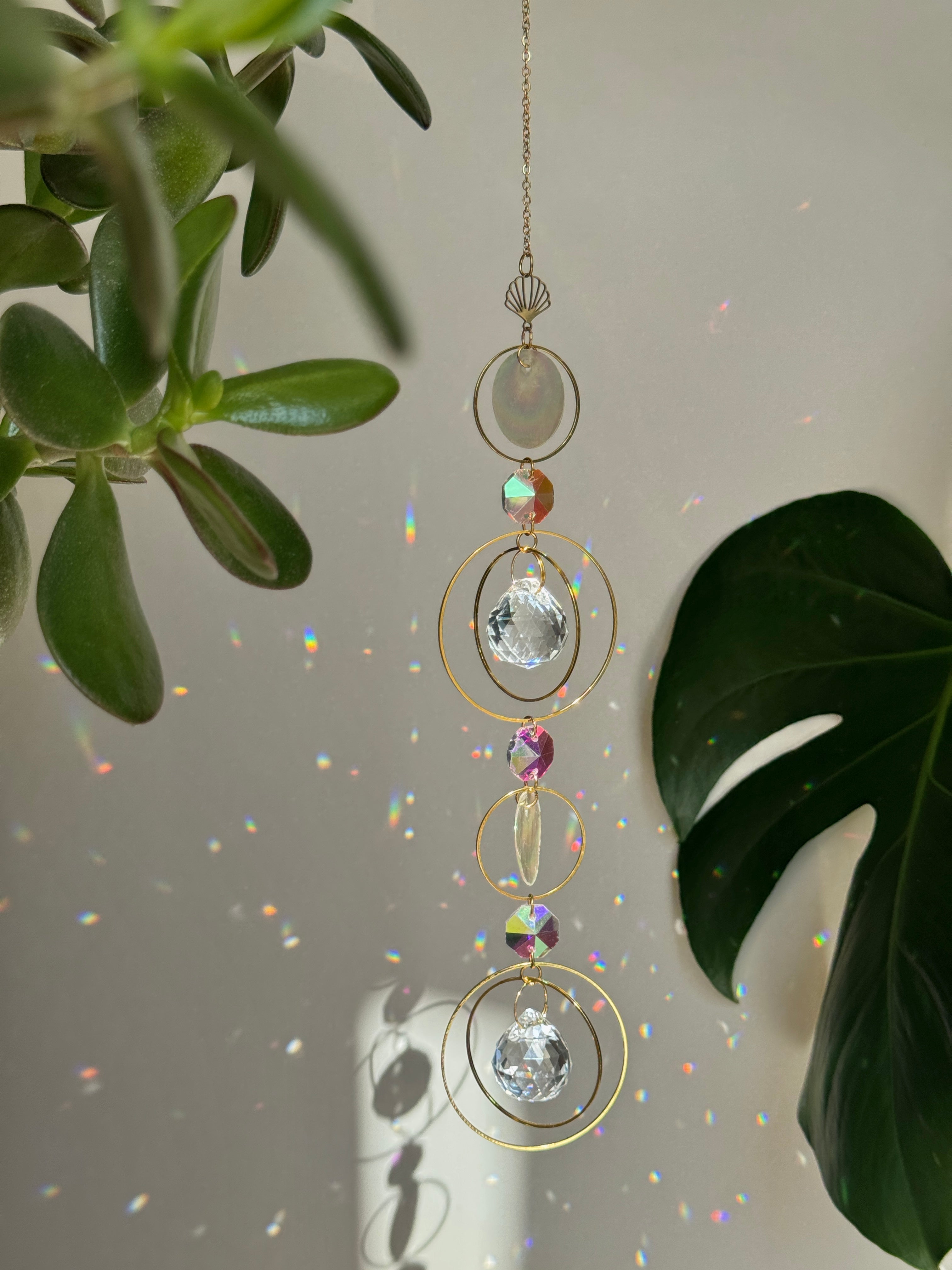 Gold celestial suncatcher with clear crystal prisms casting rainbow light reflections on a wall.