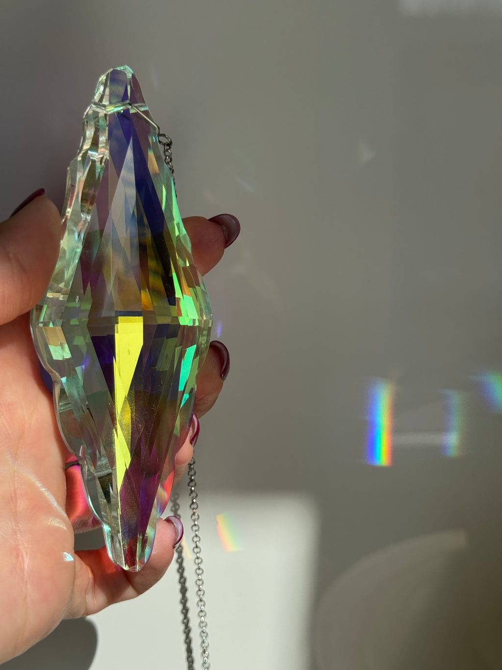 Close-up of the Aurora Borealis finish on a crystal prism (Kristall), showing the mesmerizing light refraction and silver-tone hanging hardware.