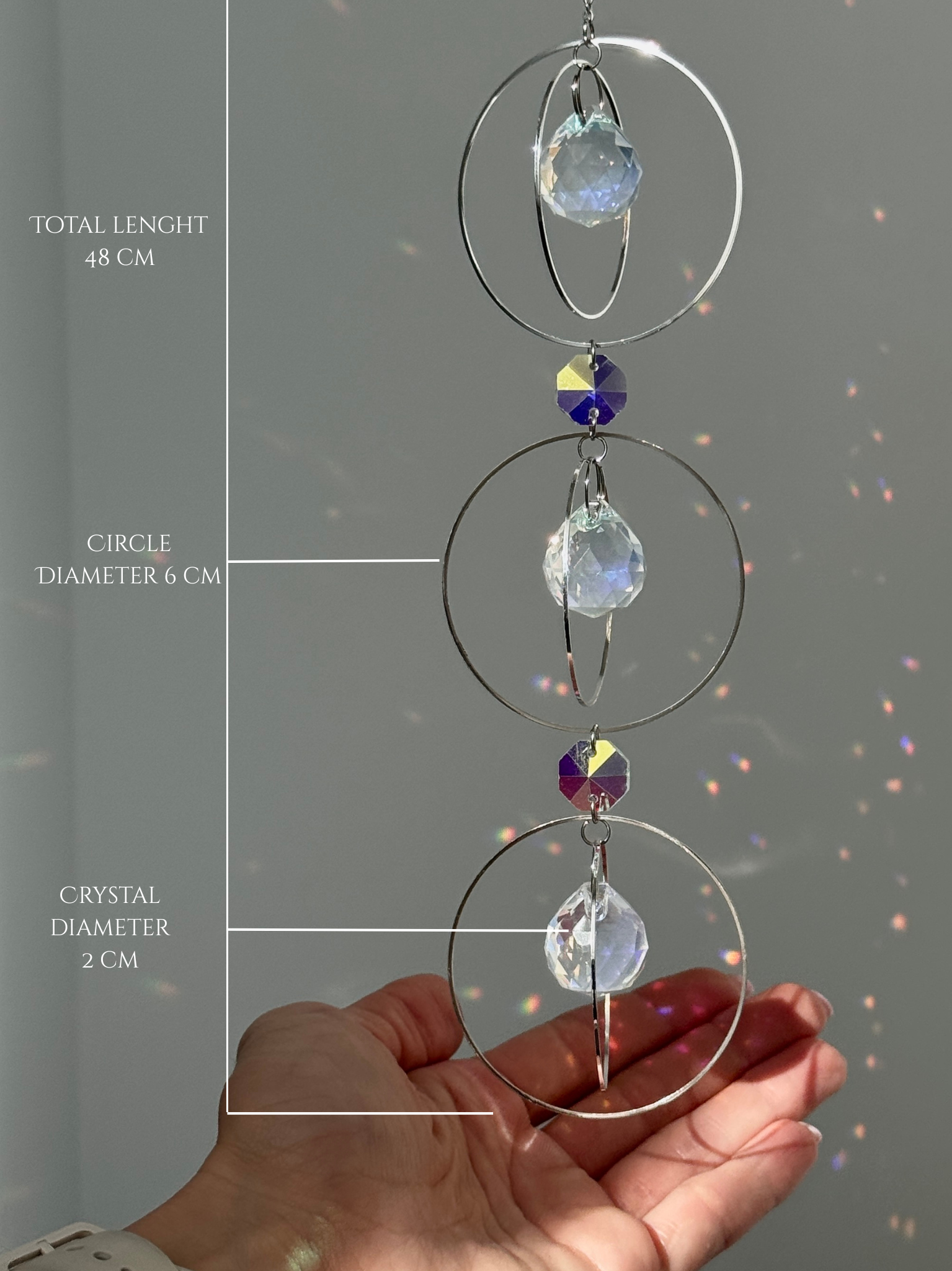 A silver-toned triple-tiered suncatcher made of stainless steel hoops. Each of the three orbits holds a clear crystal sphere with an AB coating, reflecting iridescent rainbow colors against a neutral background.