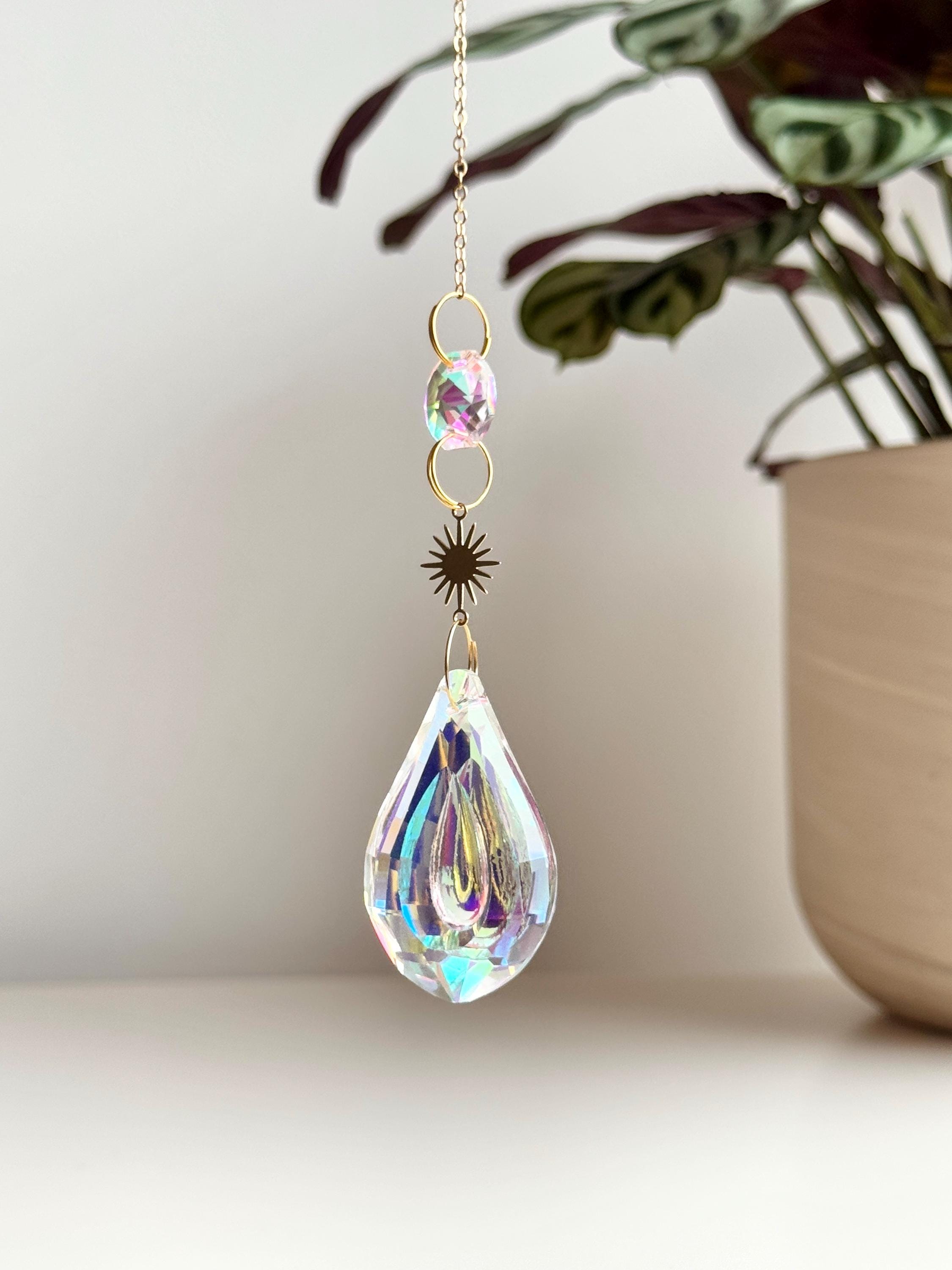 Celestial Droplet suncatcher (Sonnenfänger) with a 4cm teardrop crystal prism reflecting vibrant rainbows (Regenbogen) on a bright interior wall.