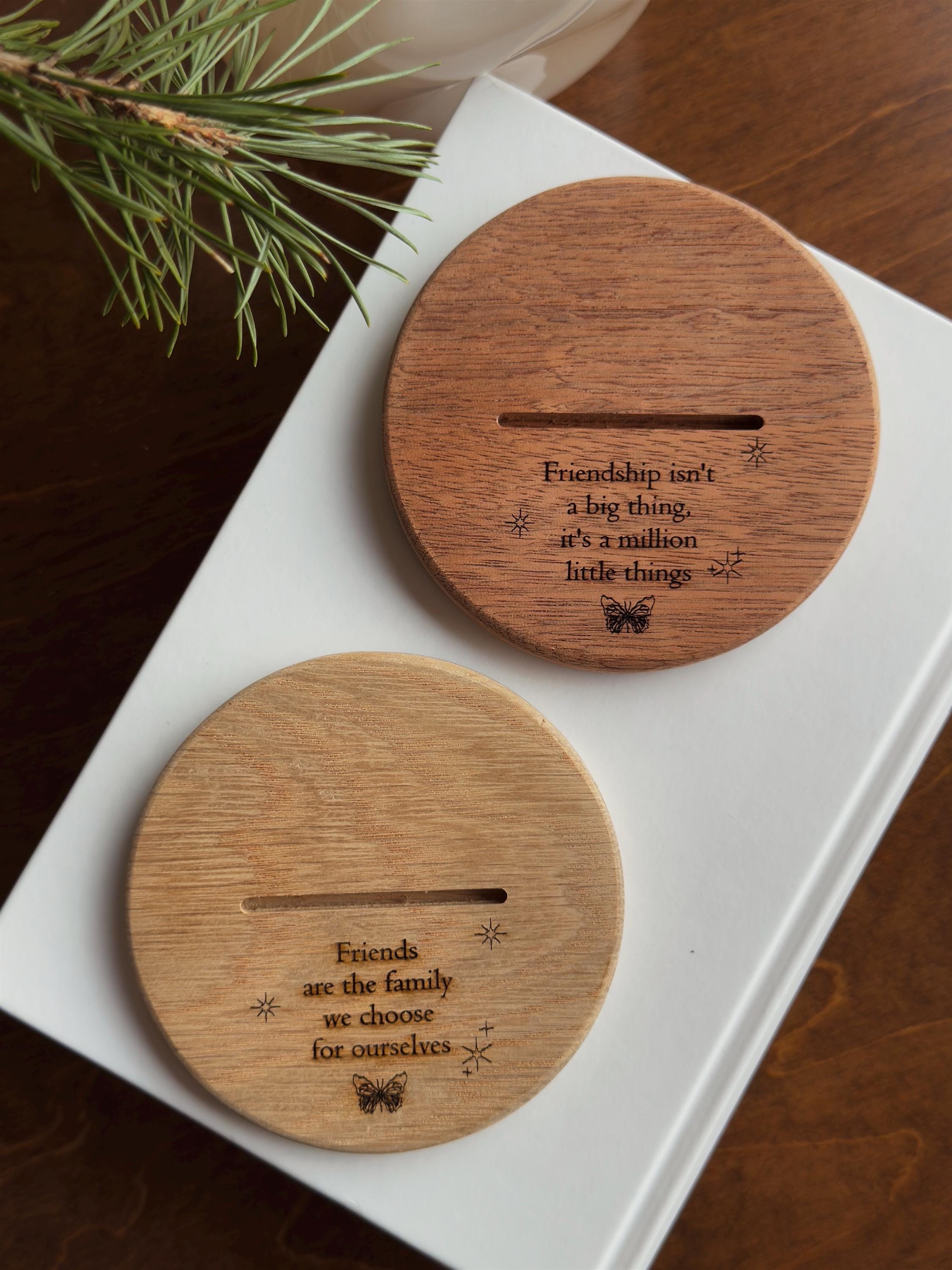 Two wooden coasters with engraved quotes on a white box.