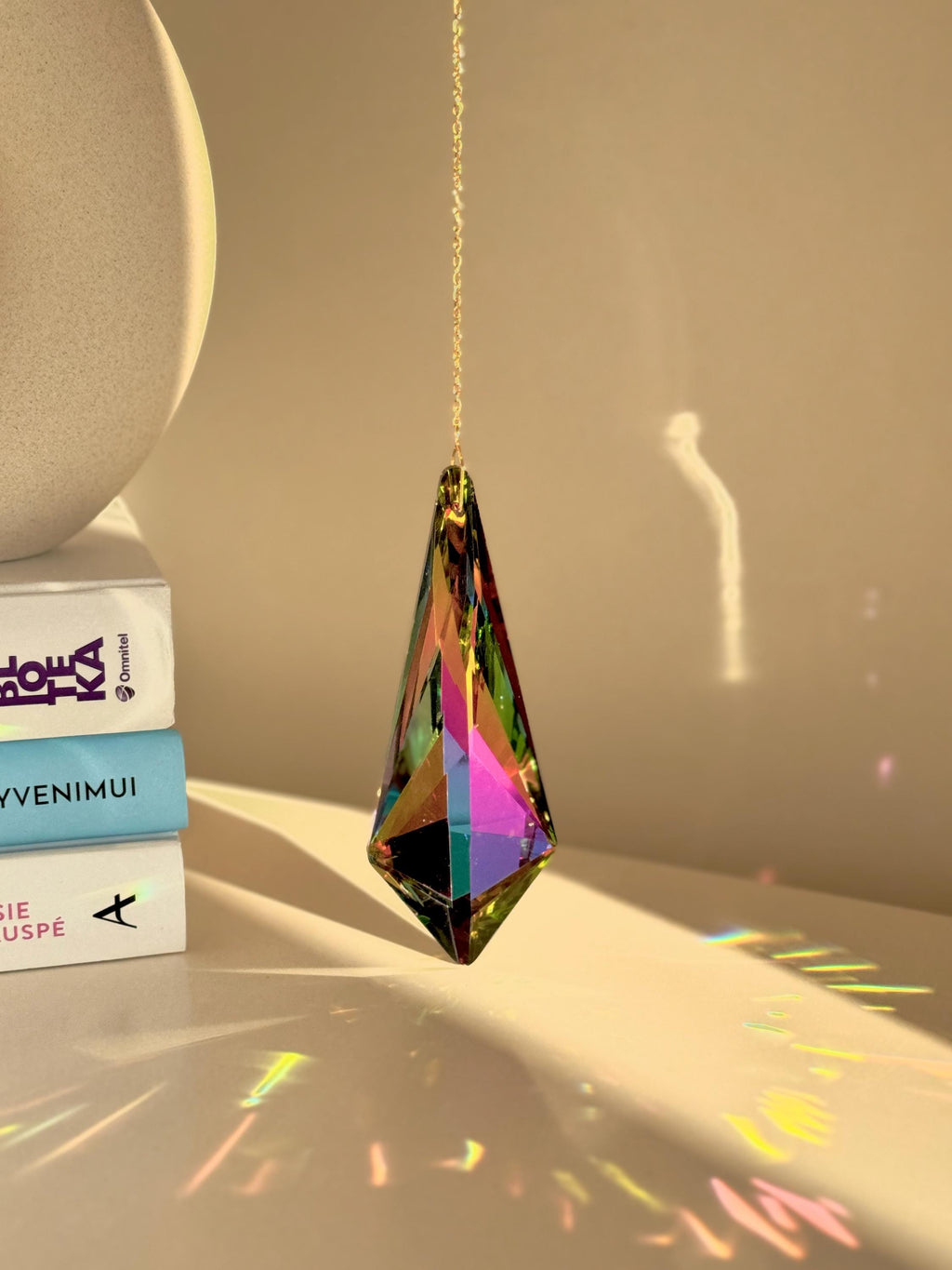 Large Vivid Geometry suncatcher (Sonnenfänger) casting deep green and gold rainbows (Regenbogen) on a white wall from a 12cm Aurora Borealis crystal.
