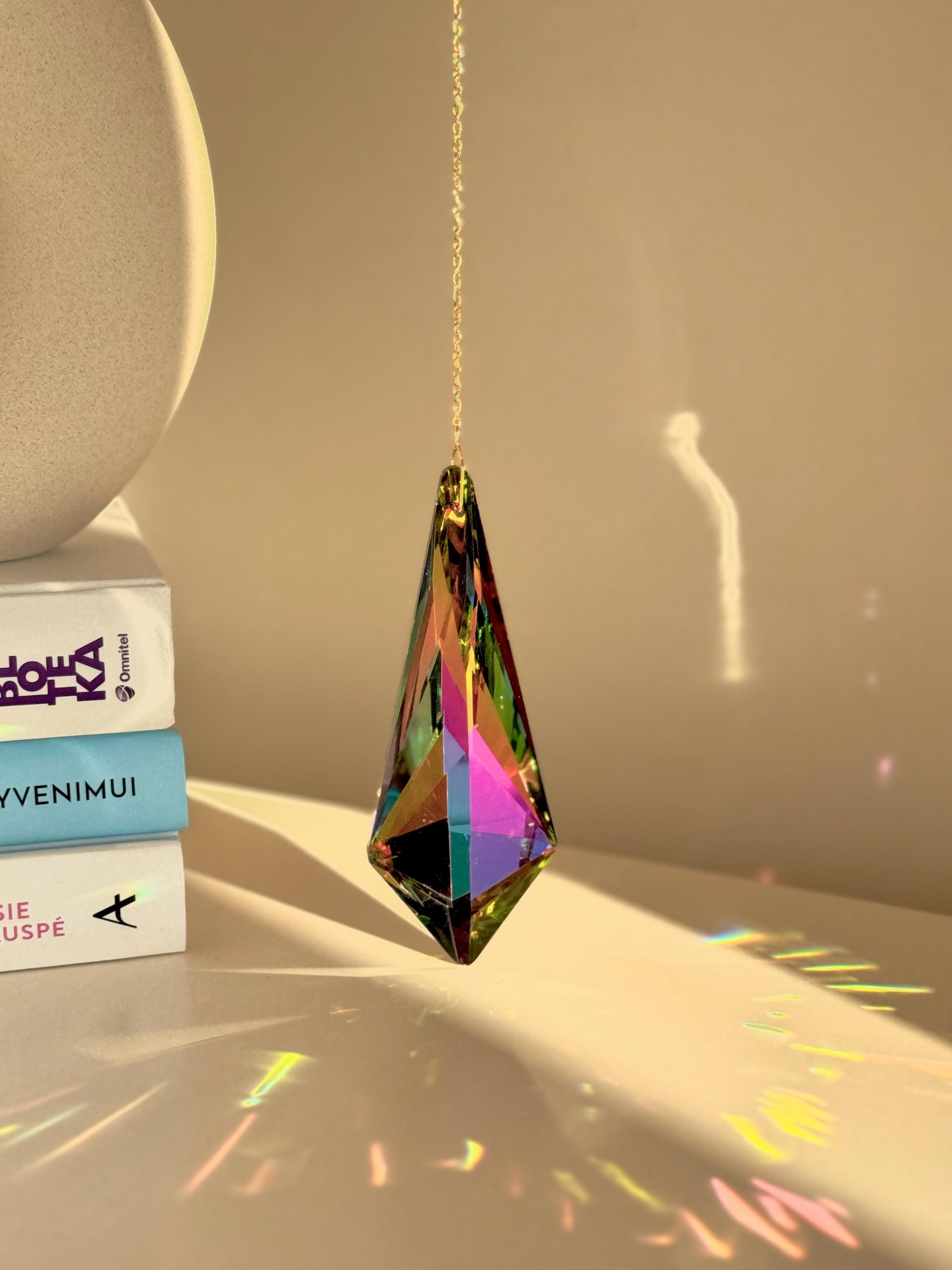 Large Vivid Geometry suncatcher (Sonnenfänger) casting deep green and gold rainbows (Regenbogen) on a white wall from a 12cm Aurora Borealis crystal.