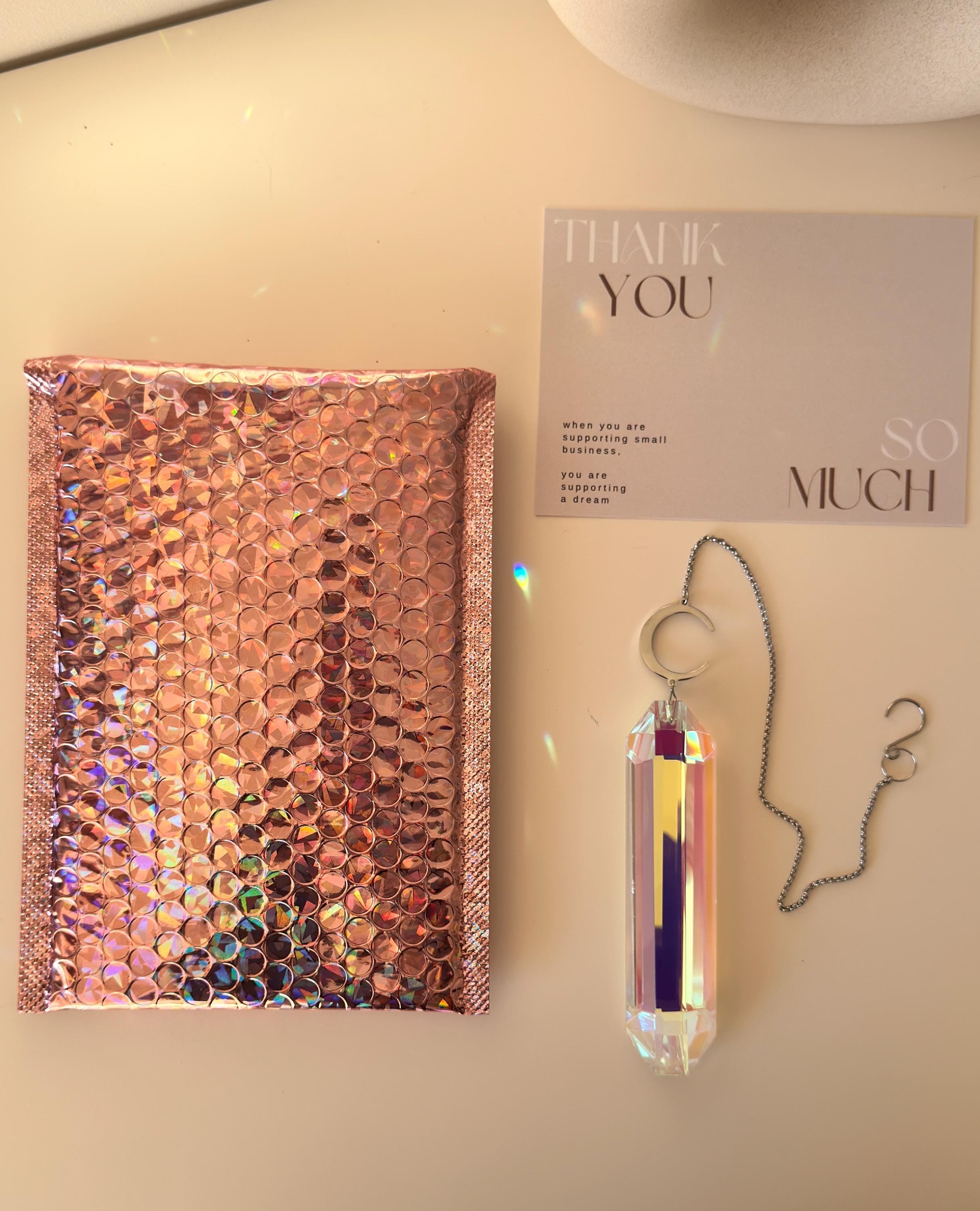 Luminescence celestial suncatcher (Sonnenfänger) with a silver crescent moon and 12 cm Aurora crystal prism scattering rainbows (Regenbogen) across a room.