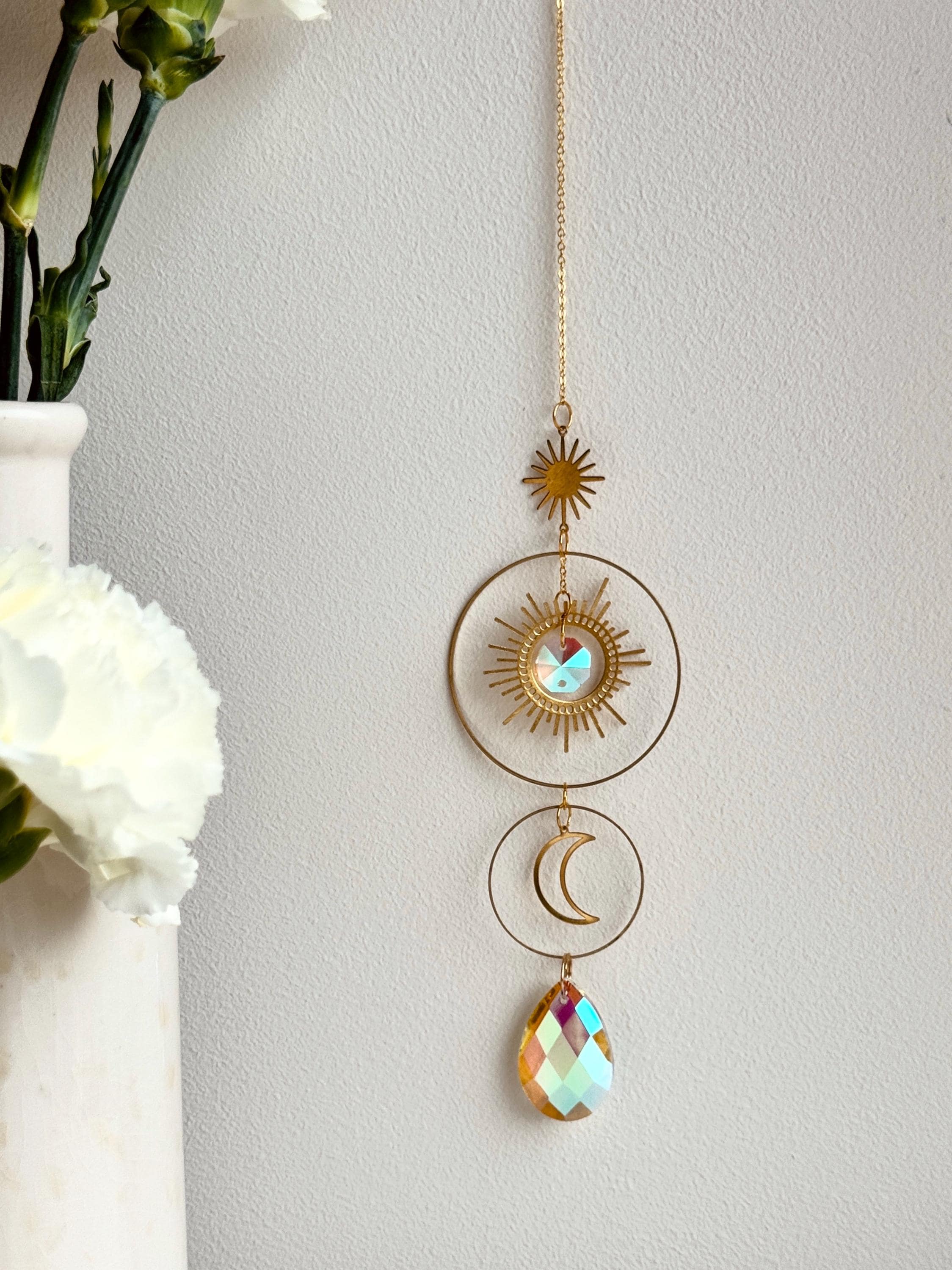 Large 4cm crystal suncatcher 'Sun's Droplet' hanging on a 40cm chain, creating brilliant rainbow patterns on a neutral wall in a sunny room.