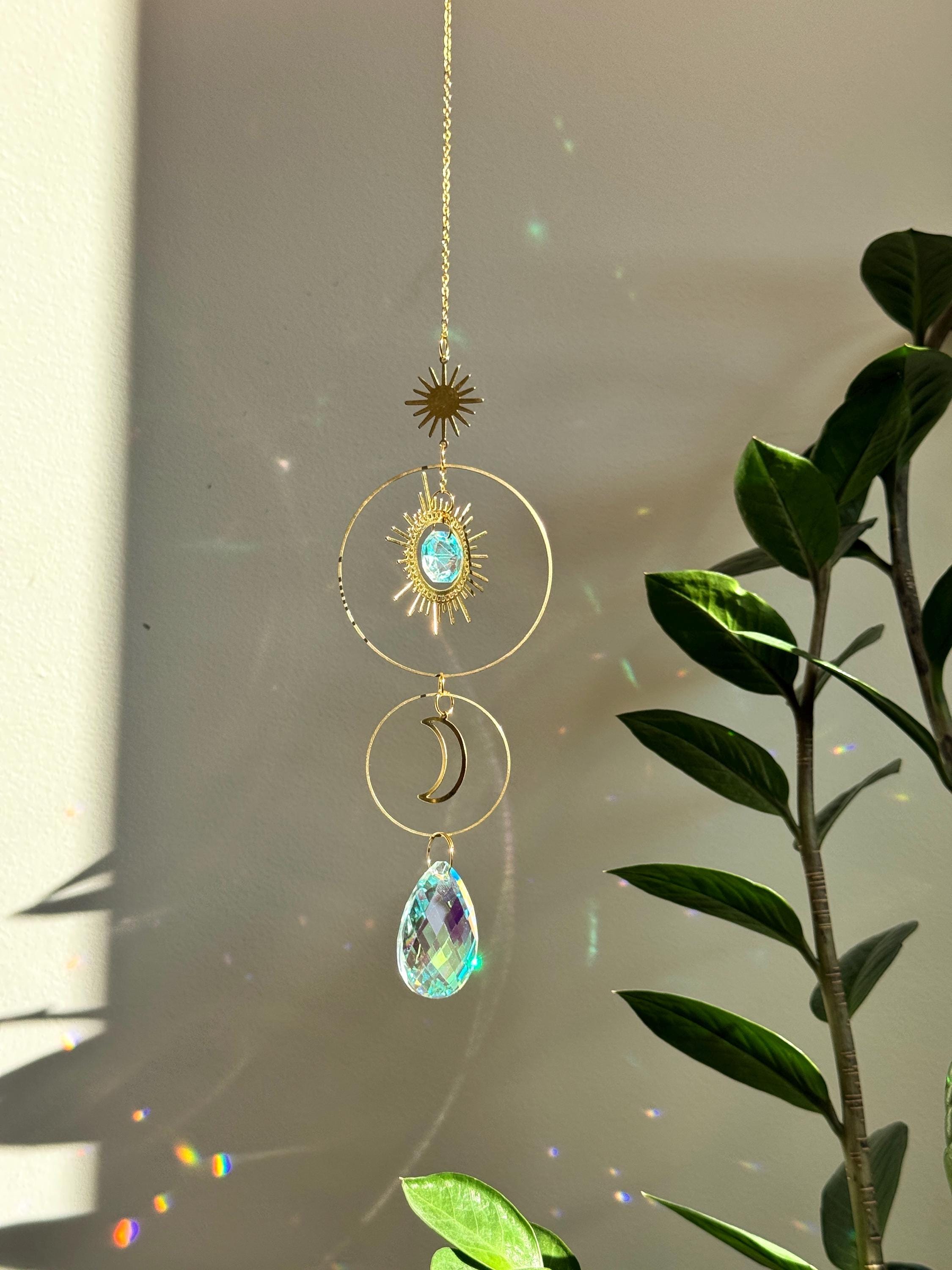 Large 4cm crystal suncatcher 'Sun's Droplet' hanging on a 40cm chain, creating brilliant rainbow patterns on a neutral wall in a sunny room.