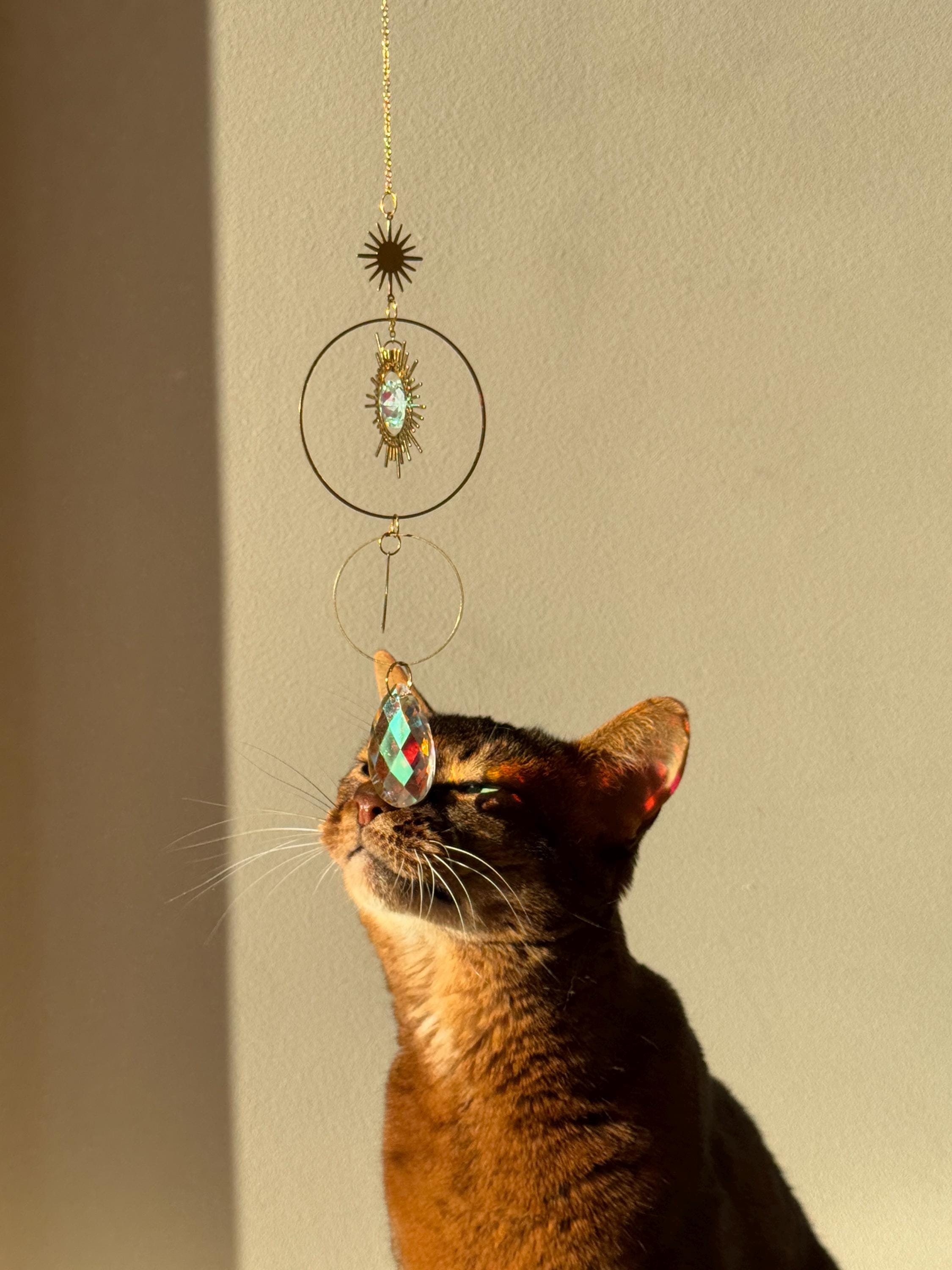Large 4cm crystal suncatcher 'Sun's Droplet' hanging on a 40cm chain, creating brilliant rainbow patterns on a neutral wall in a sunny room.