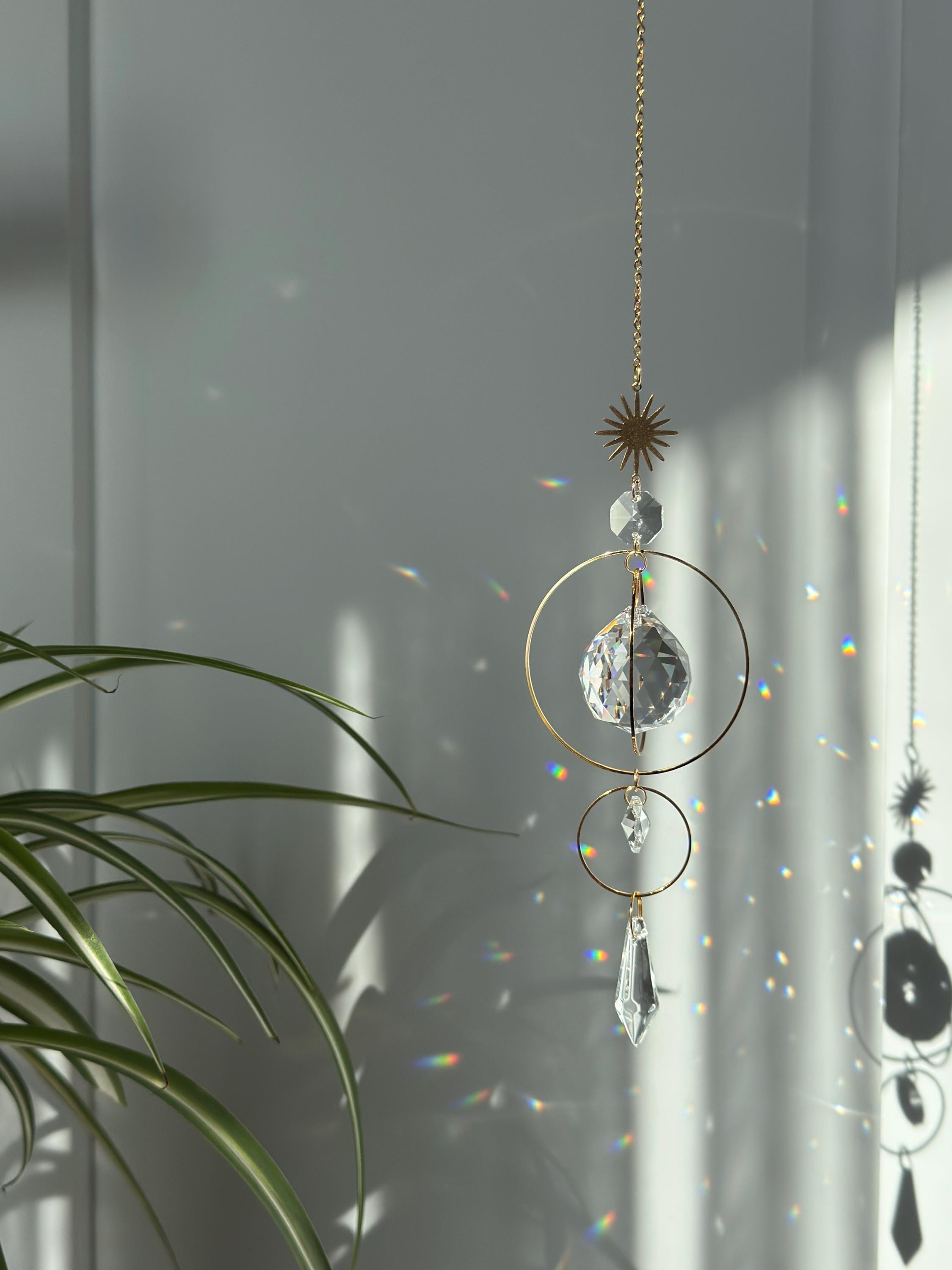 Gold celestial suncatcher with clear crystal prisms casting rainbow light reflections on a wall.