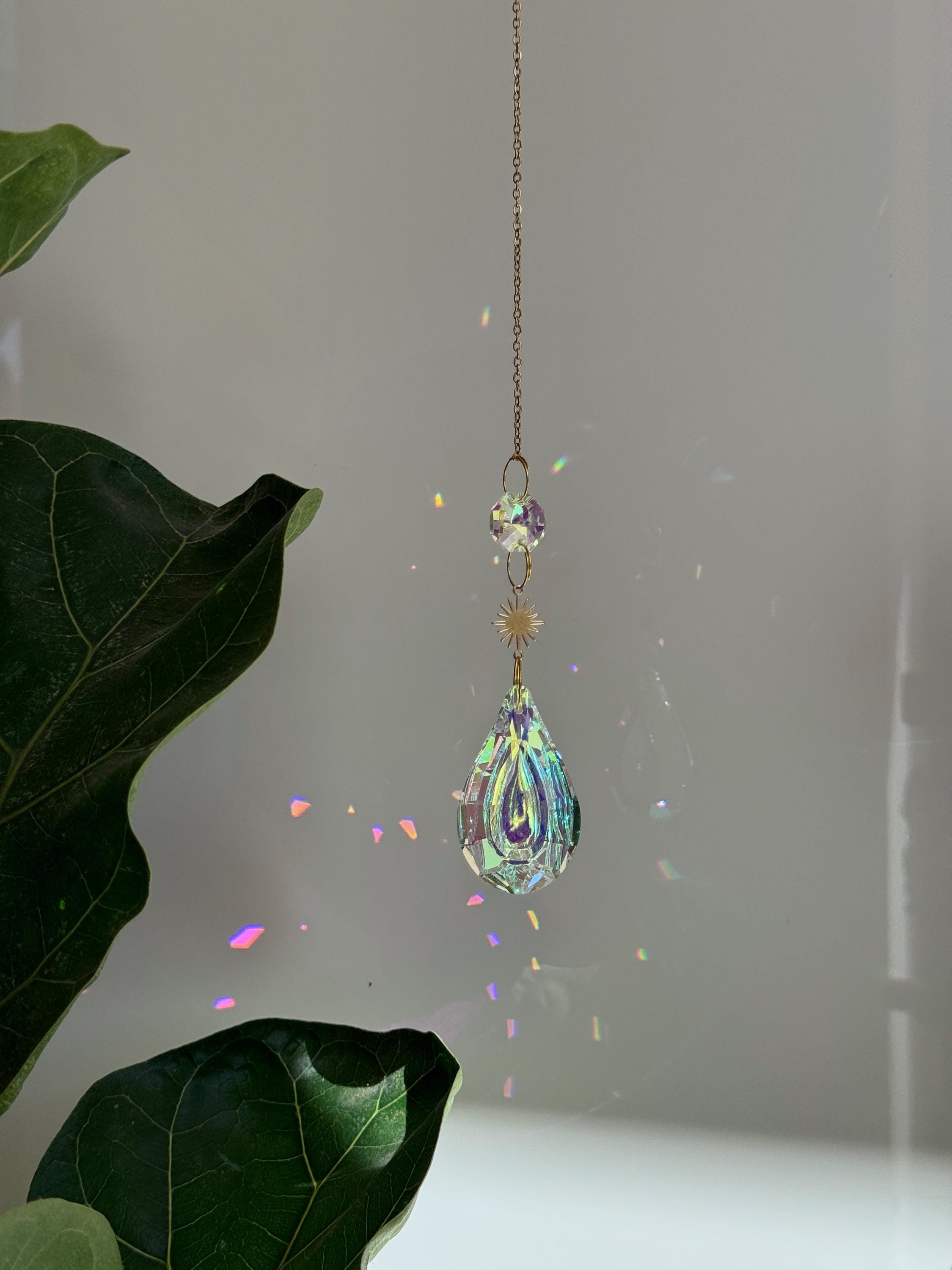 Celestial Droplet suncatcher (Sonnenfänger) with a 4cm teardrop crystal prism reflecting vibrant rainbows (Regenbogen) on a bright interior wall.