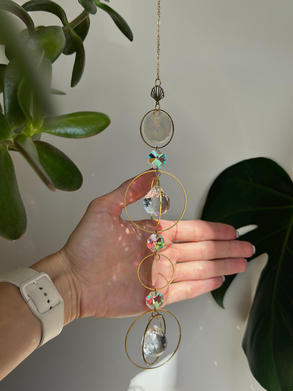 Gold celestial suncatcher with clear crystal prisms casting rainbow light reflections on a wall.