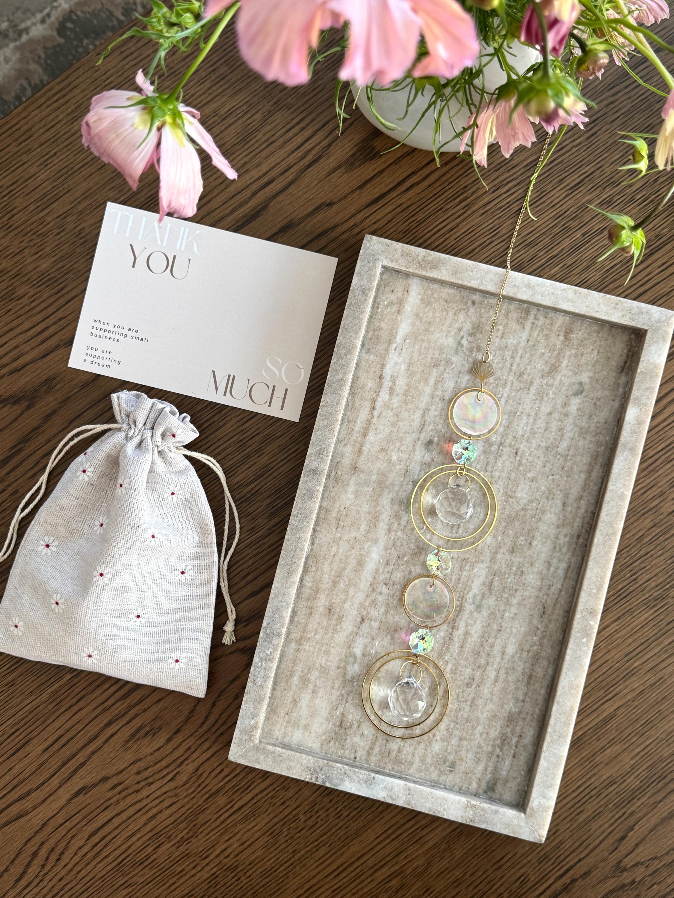 Handmade gold suncatcher tucked inside a signature cream linen gift bag, sustainable gift packaging.
