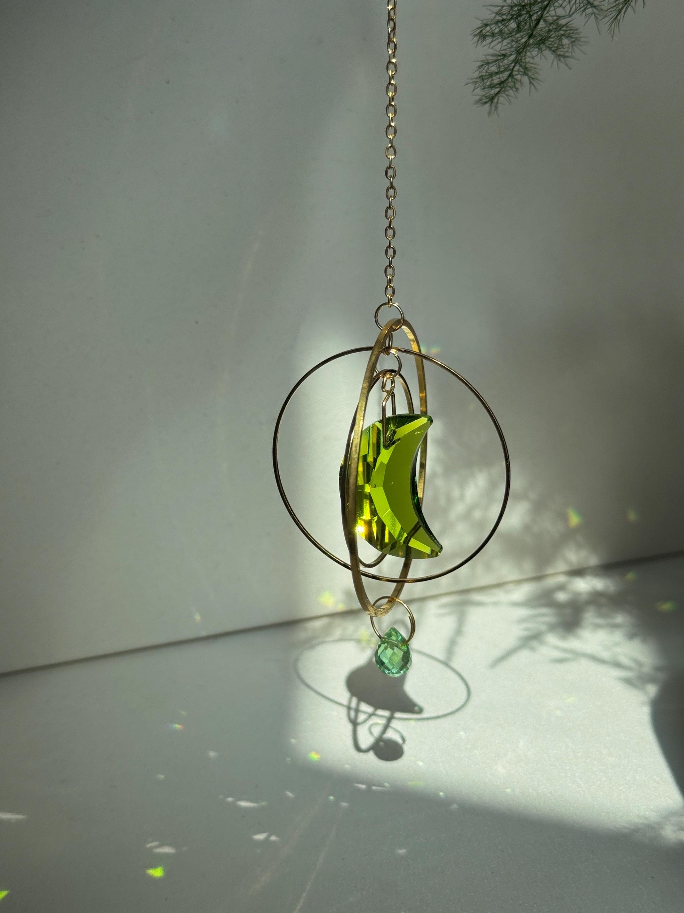 Handmade green crescent moon crystal suncatcher "Over the Moon" casting magical rainbows on a wall. Celestial gold ring window decor and rainbow maker (Sonnenfänger)