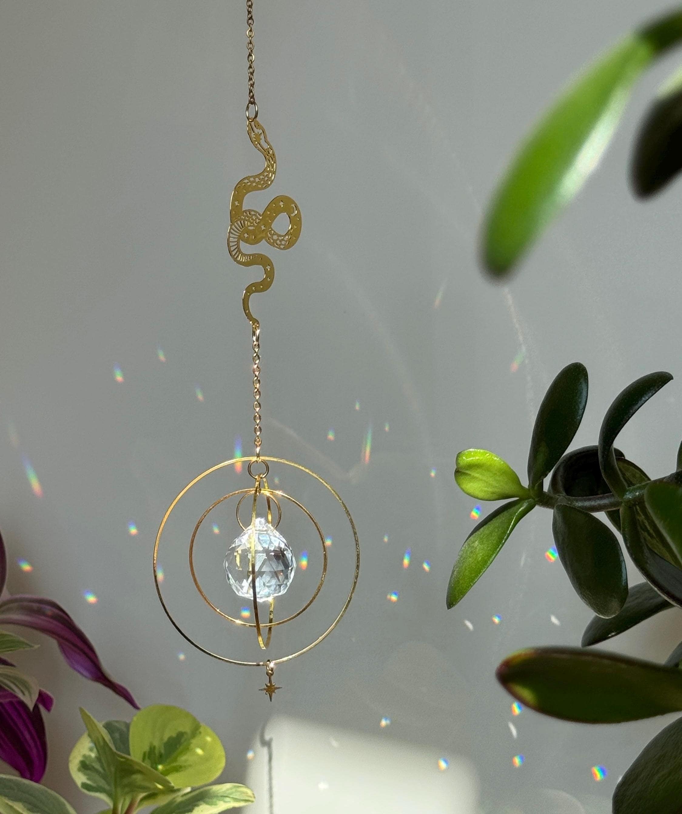 Decorative hanging crystal with gold chain against a blurred natural background
