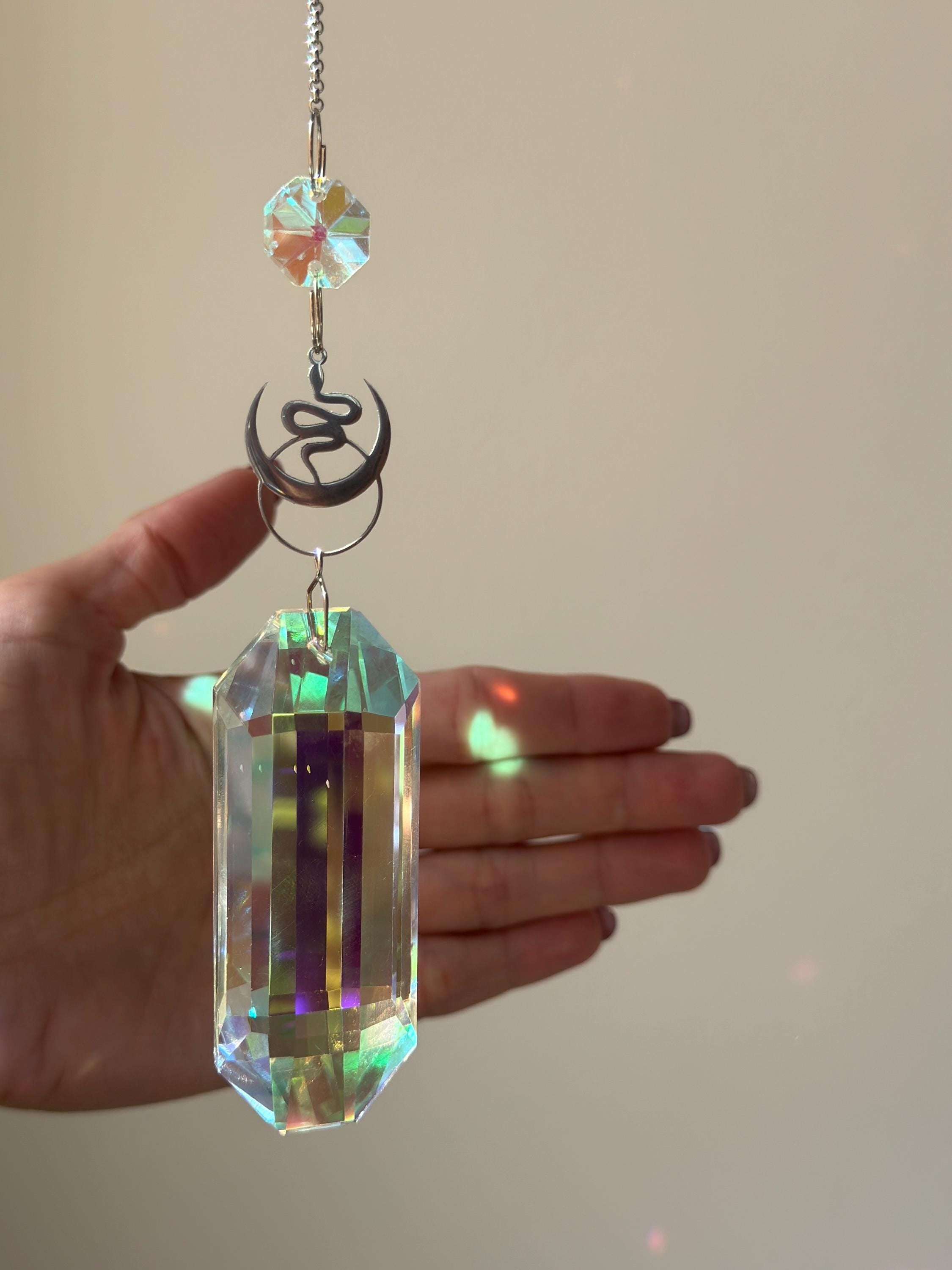 Lunar Obelisk celestial suncatcher (Sonnenfänger) featuring a gold snake charm and a large 7.5cm faceted crystal prism scattering rainbows (Regenbogen).