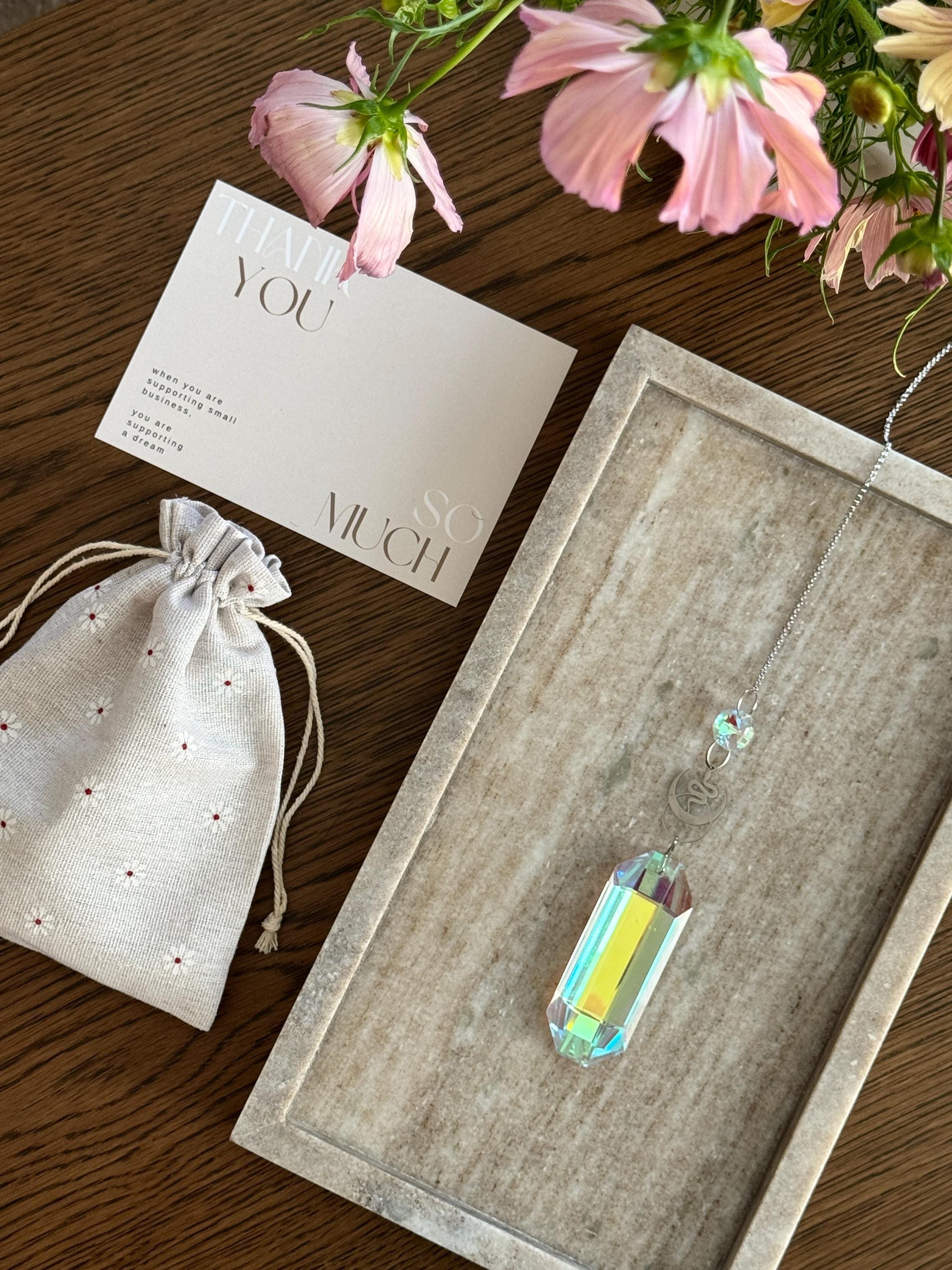 Lunar Obelisk celestial suncatcher (Sonnenfänger) featuring a gold snake charm and a large 7.5cm faceted crystal prism scattering rainbows (Regenbogen).