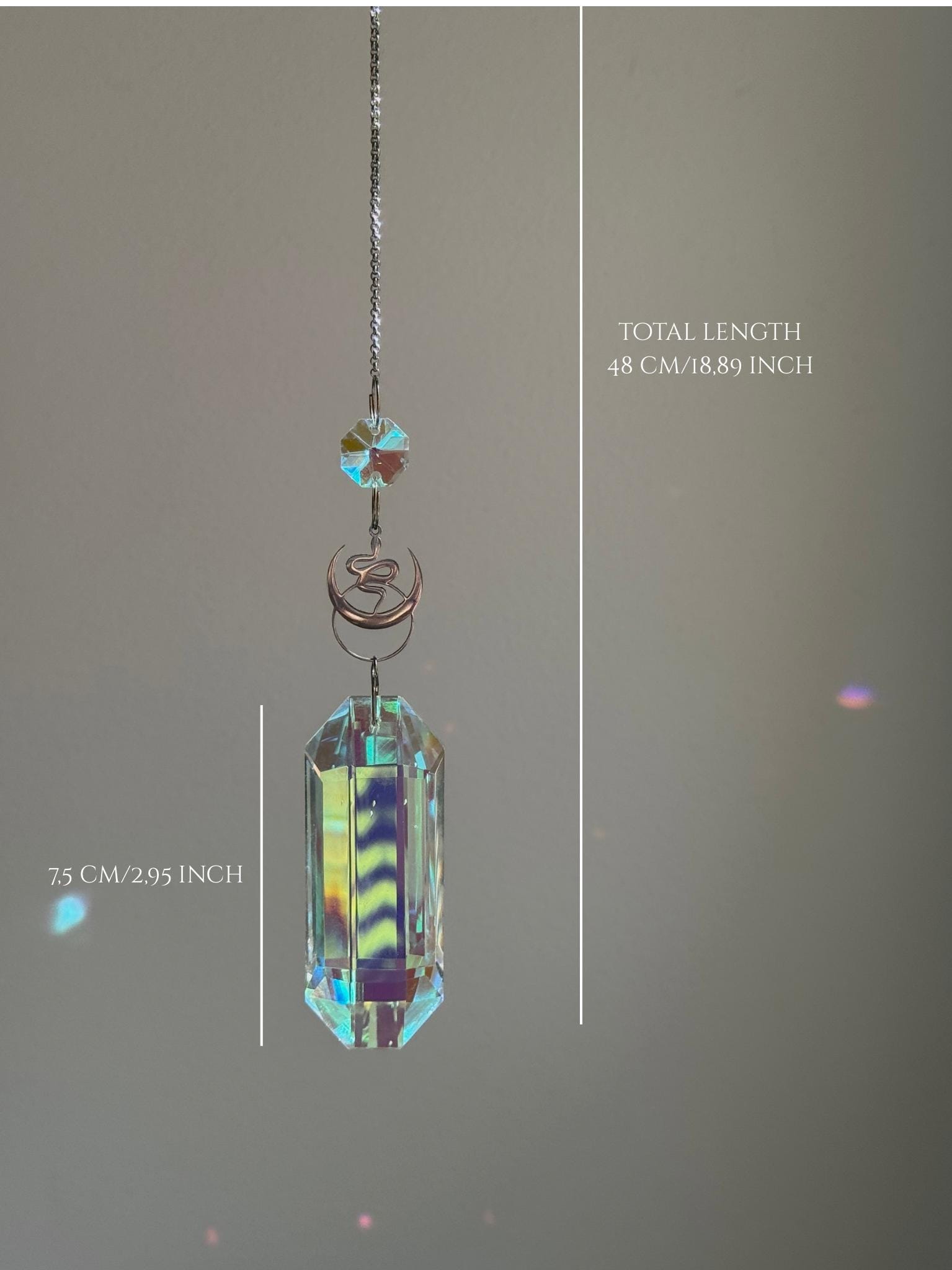 Close-up of the intricate snake charm and faceted crystal obelisk (Kristall) against a sunlit window background.