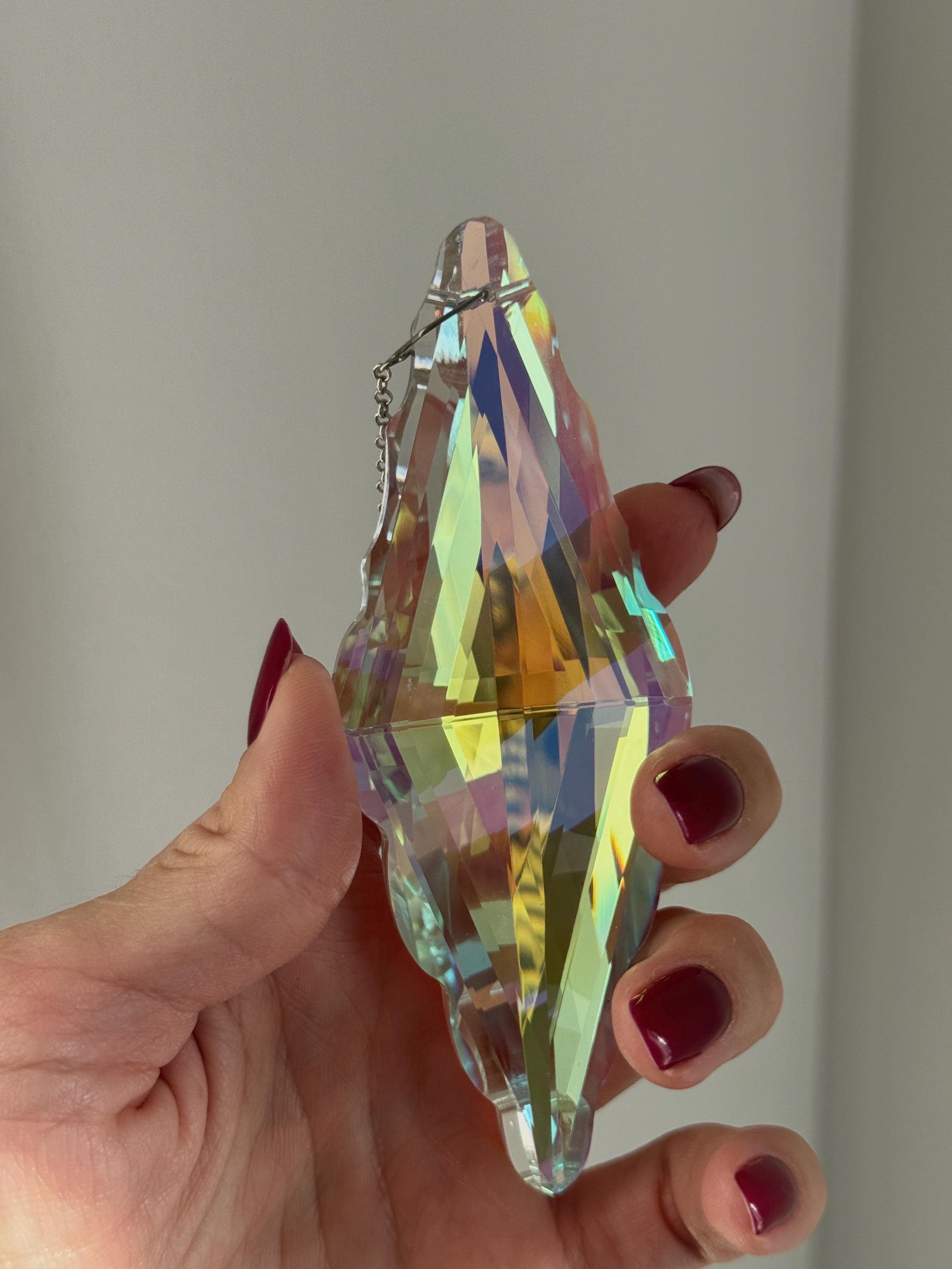 Close-up of the Aurora Borealis finish on a crystal prism (Kristall), showing the mesmerizing light refraction and silver-tone hanging hardware.