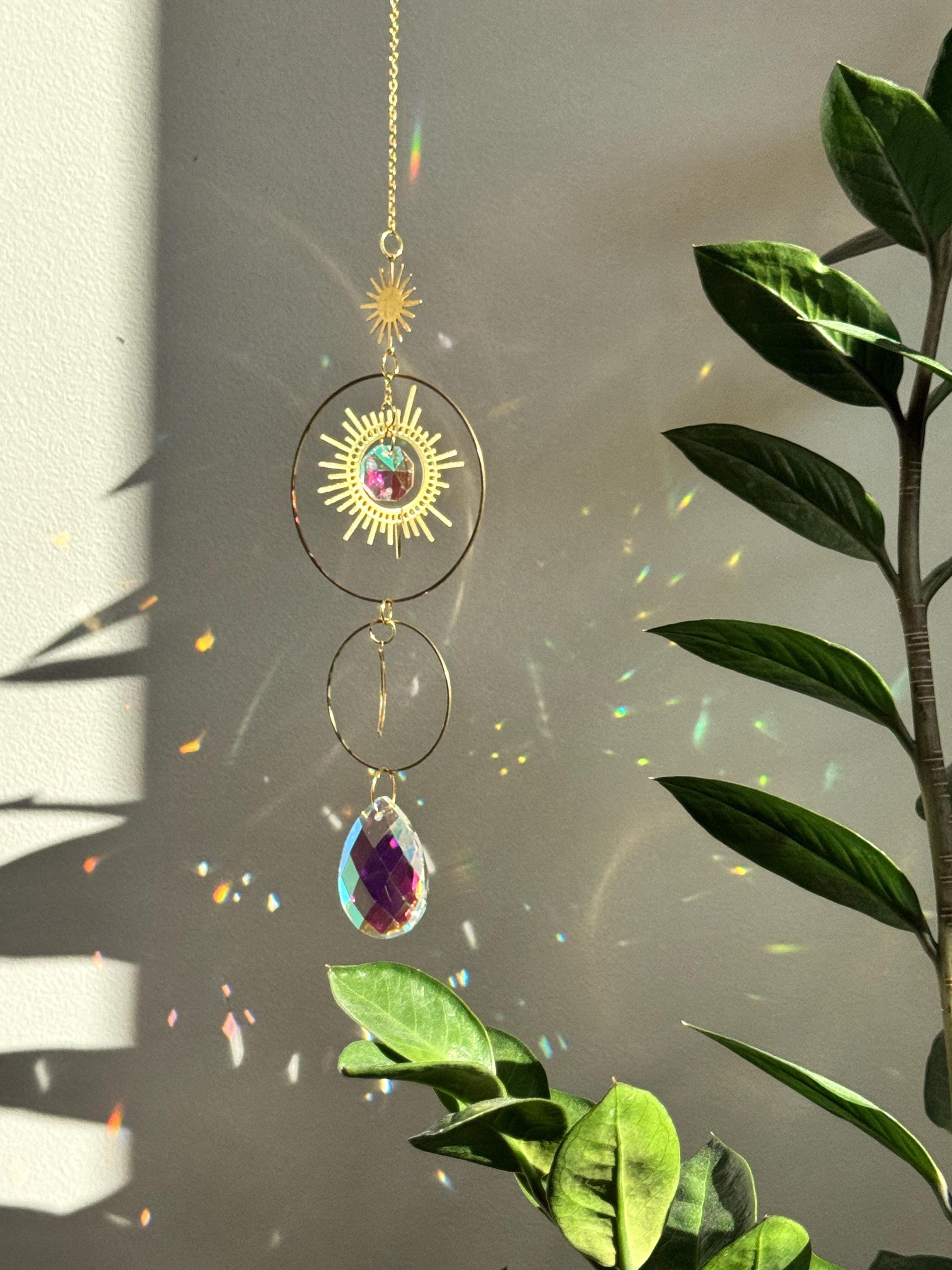 Large 4cm crystal suncatcher 'Sun's Droplet' hanging on a 40cm chain, creating brilliant rainbow patterns on a neutral wall in a sunny room.