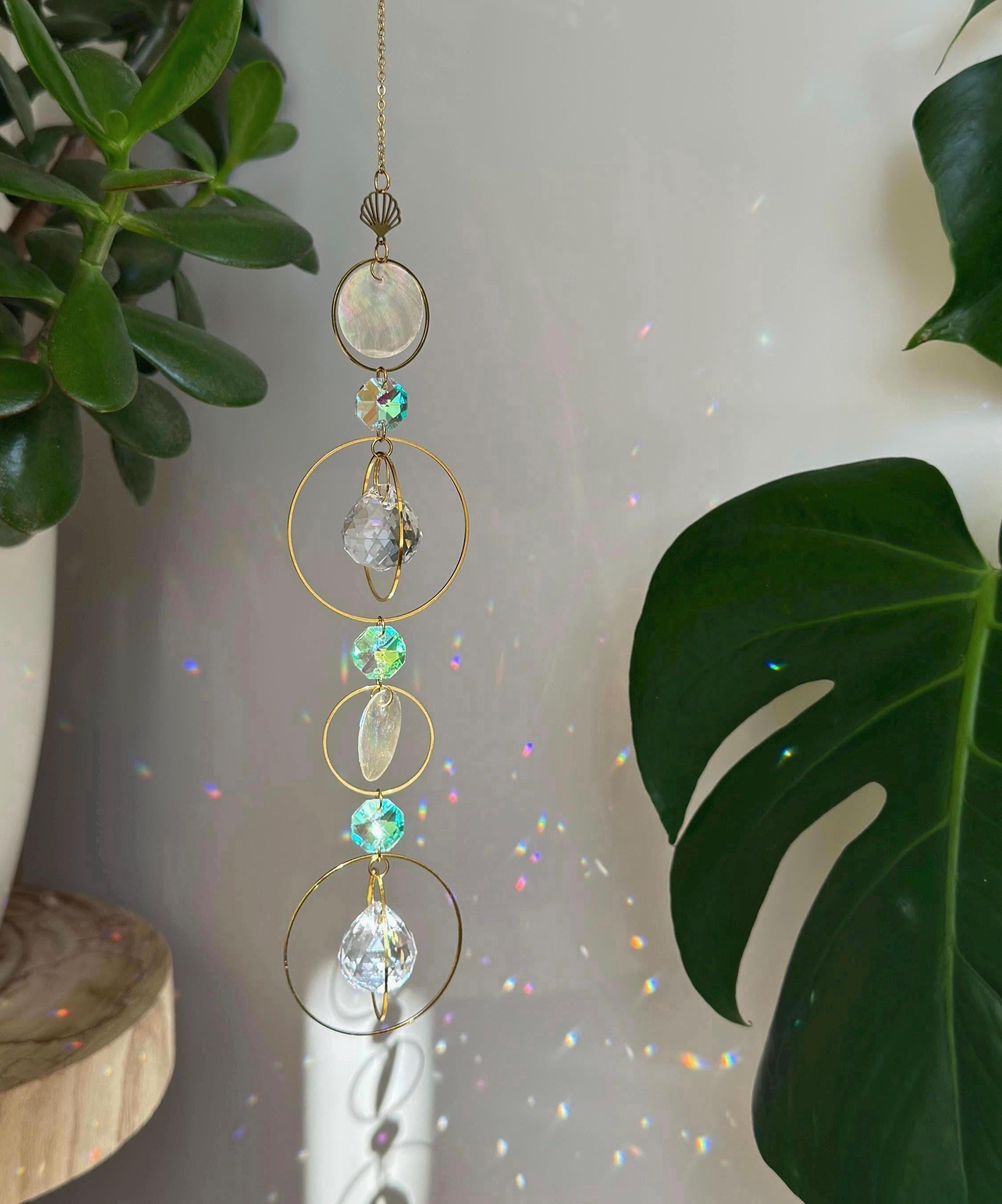 Gold celestial suncatcher with clear crystal prisms casting rainbow light reflections on a wall.
