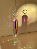 Luminescence celestial suncatcher (Sonnenfänger) with a silver crescent moon and 12 cm Aurora crystal prism scattering rainbows (Regenbogen) across a room.