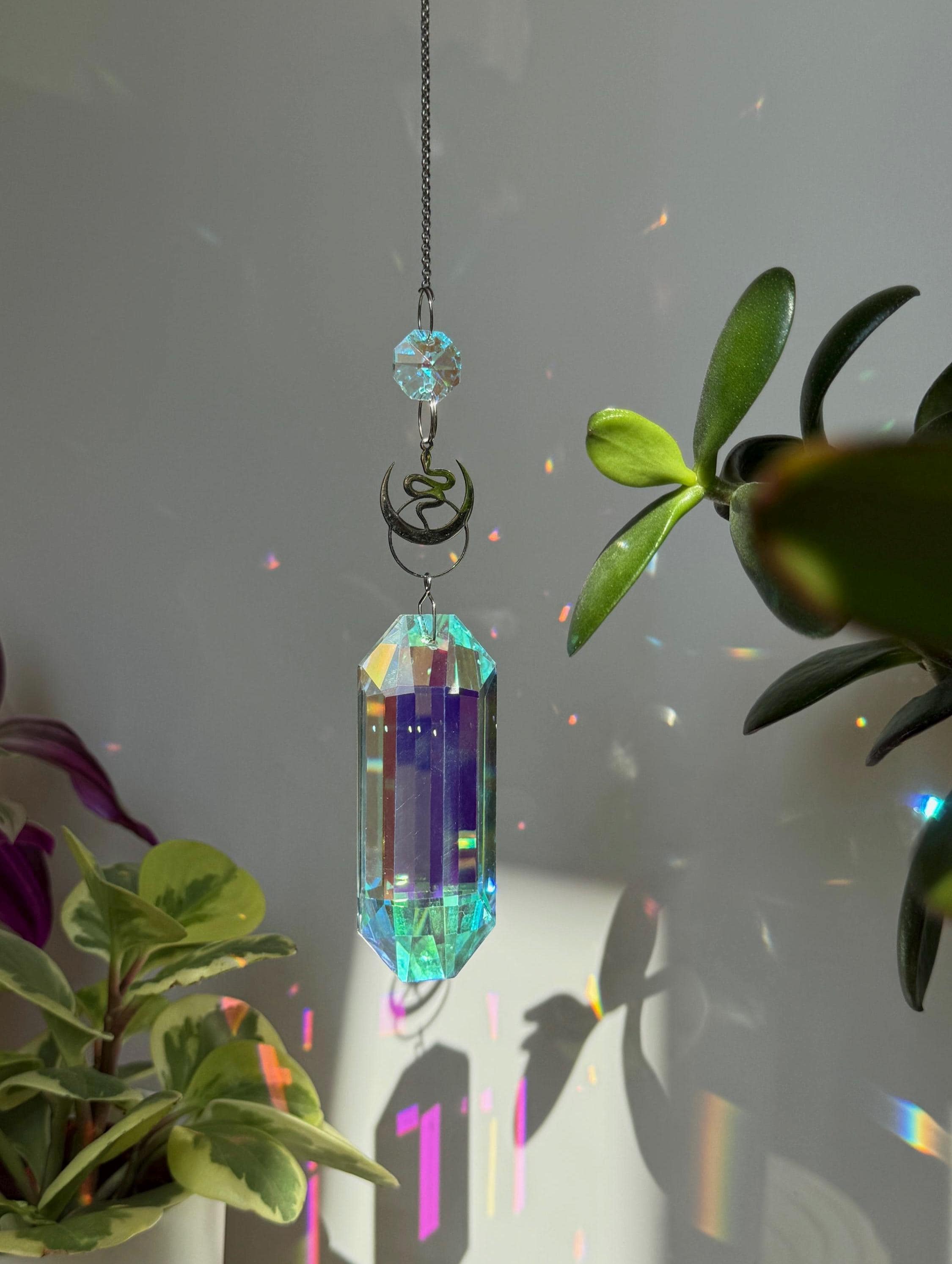 Lunar Obelisk celestial suncatcher (Sonnenfänger) featuring a gold snake charm and a large 7.5cm faceted crystal prism scattering rainbows (Regenbogen).