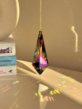 Large Vivid Geometry suncatcher (Sonnenfänger) casting deep green and gold rainbows (Regenbogen) on a white wall from a 12cm Aurora Borealis crystal.